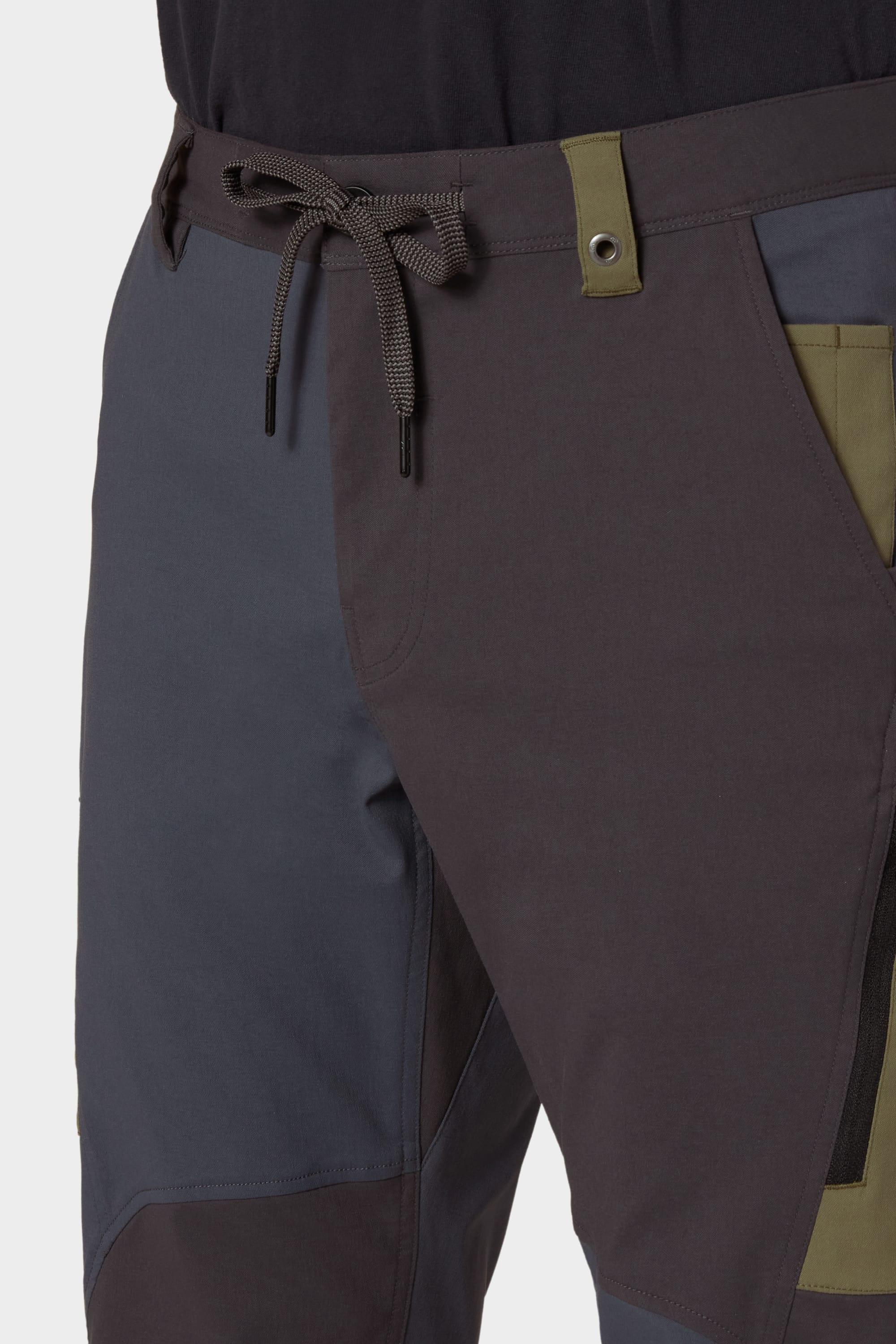 Close-up of a person wearing the 686 Mens Anything Cargo Pant - Relaxed Fit by 686, featuring a drawstring waist, grey and olive green color-blocked design, crafted from breathable fabric, shown from the upper thigh and hip area.