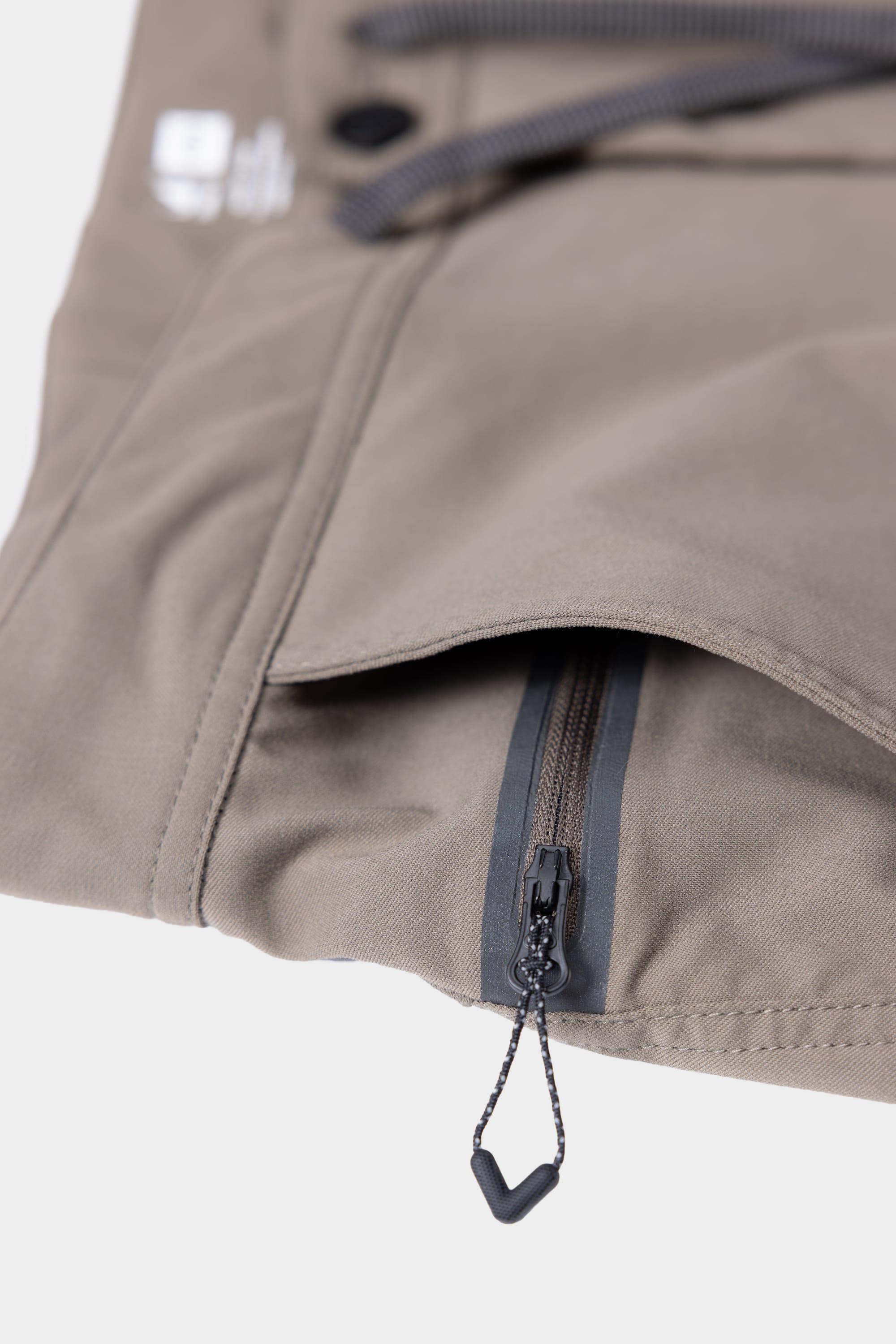Close-up of the 686 Mens Platform Bike Pant - Relaxed Fit in khaki, featuring a zippered pocket with a black zipper pull and visible stitching details.