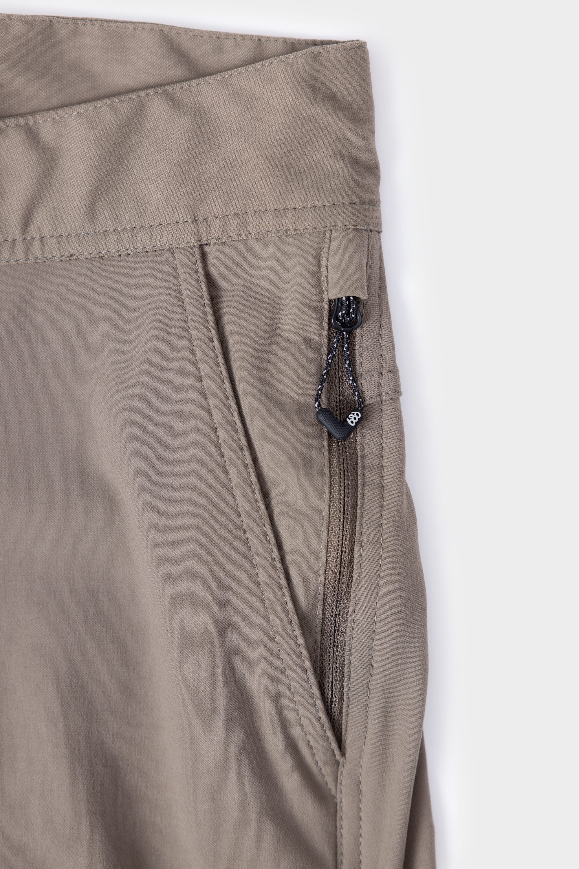 Close-up of the 686 Mens Platform Bike Pant - Relaxed Fit in khaki, highlighting the pocket’s zipper with black pull tab, plus stitching and fabric texture details.