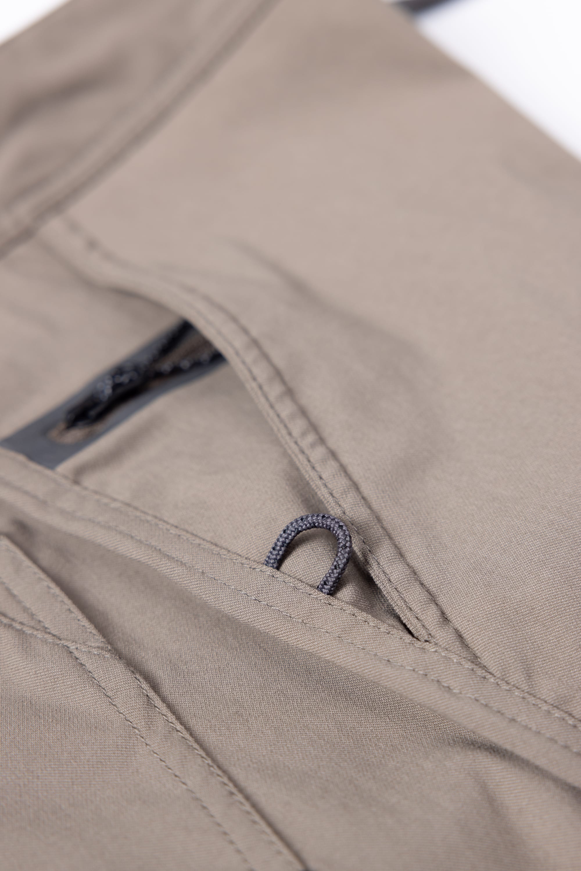 Close-up of a pocket on the 686 Mens Platform Bike Pant - Relaxed Fit, featuring khaki fabric, a black zipper, and a small black fabric loop at the opening.