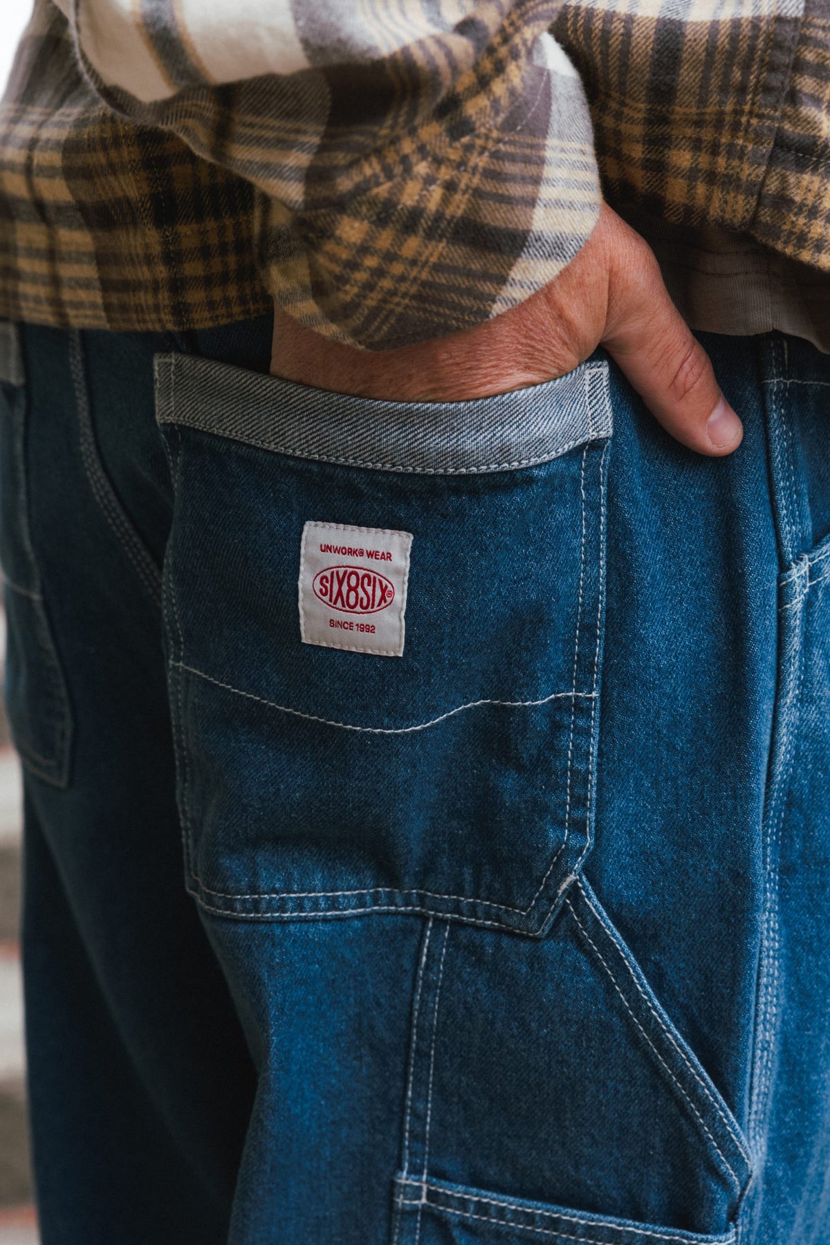 Close-up of a hand in the back pocket of 686 Men’s Unwork® Hammerhead Denim Pant, featuring a rectangular patch with red branding.
