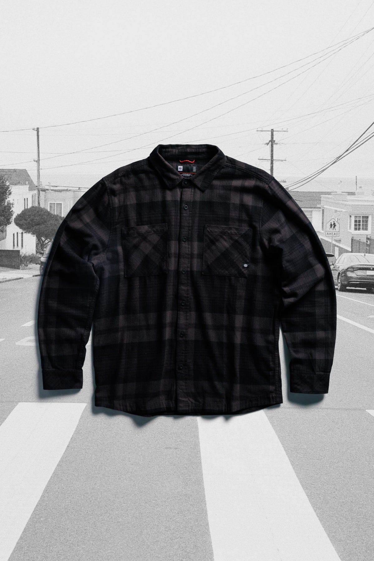 686 Men’s SMARTY® Headwall Flannel in a long-sleeved black and dark gray plaid, featuring two chest pockets and centered over a crosswalk background.