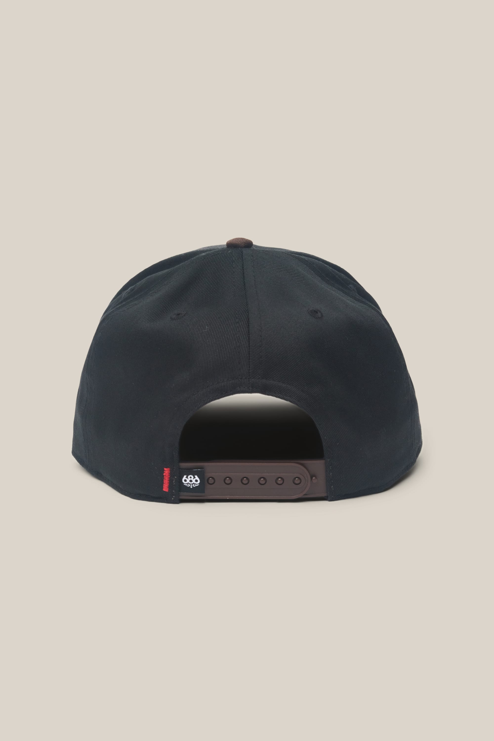 The 686 High-Pro Ses Two Tone Structured 5 Panel Hat by 686 is a black men's snapback with an adjustable strap and a small black-and-white tag at the back. Made from 100% cotton, it's displayed against a plain light beige background.