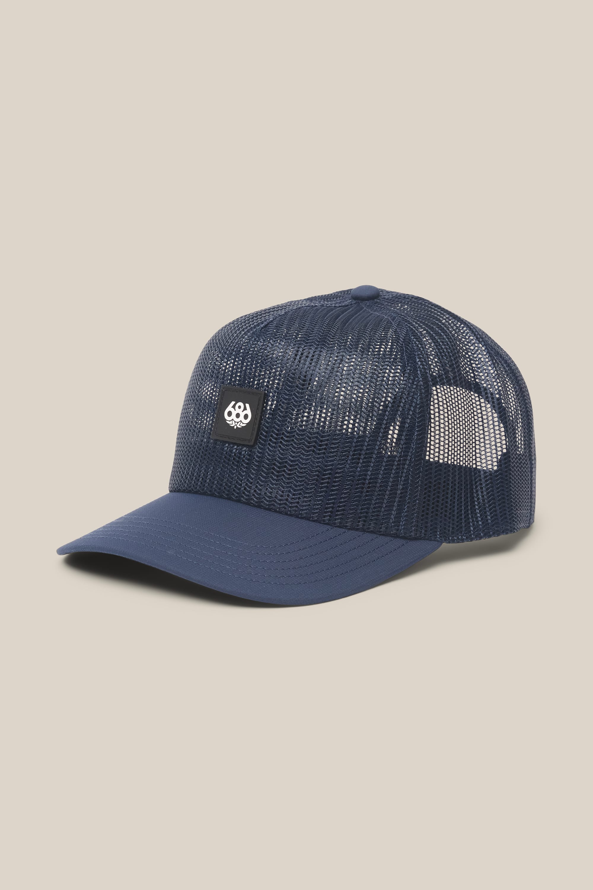 The 686 High-Pro Knockout Structured 5 Panel Hat by 686 features a navy blue mesh design with a curved brim and a small black-and-white logo patch on the front panel, shown stylishly against a light beige background.