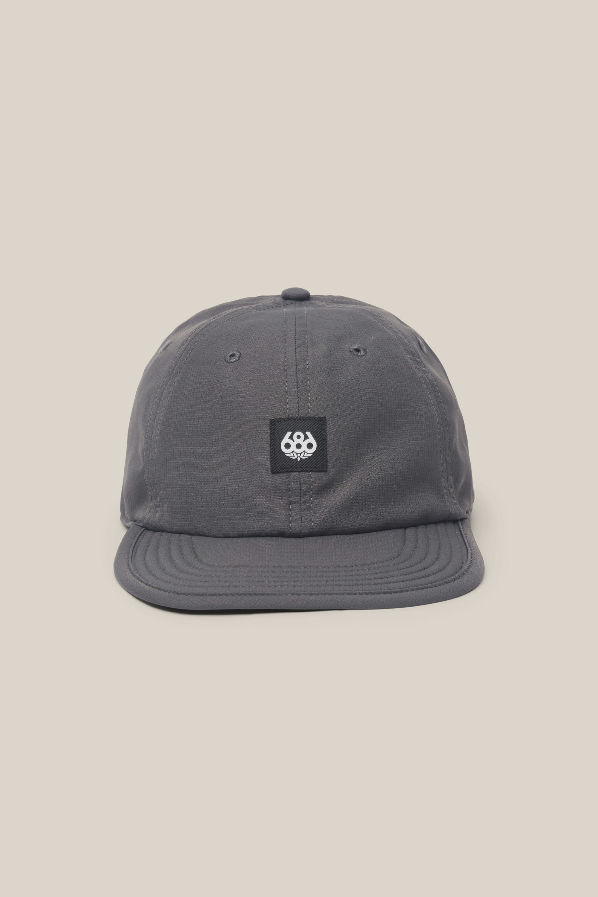The 686 Low-Pro Adventure Unstructured 6 Panel Hat by 686 is a gray men's polyester hat with a small black patch and white logo on the front, shown against a plain beige background.