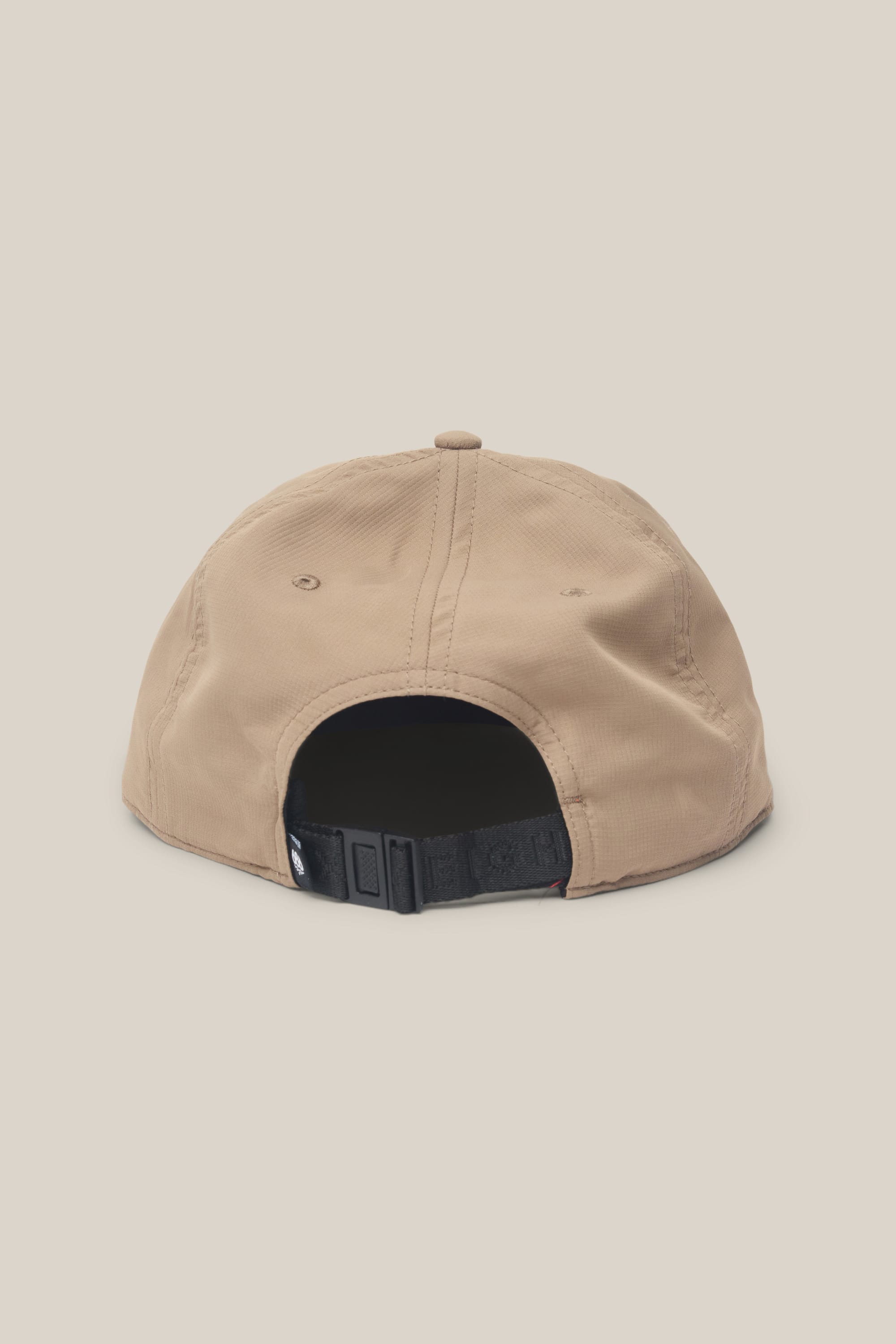 The 686 Low-Pro Adventure Unstructured 6 Panel Hat by 686 is a beige polyester-cotton baseball cap, displayed from the back with a black adjustable strap and buckle, set against a plain off-white background.
