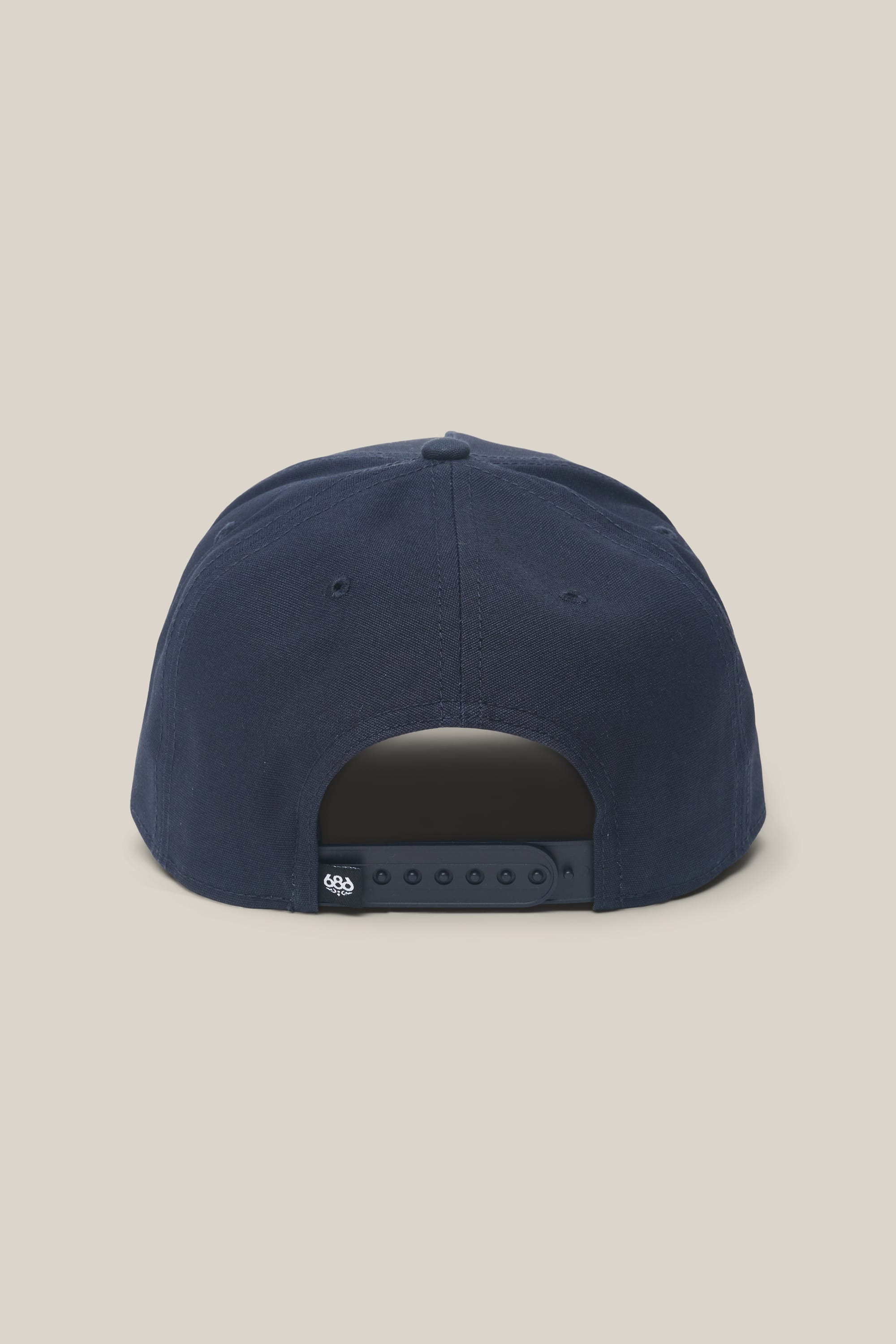 The 686 High-Pro 92 Structured 5 Panel Hat by 686 is shown from the back in navy blue polyester cotton, featuring an adjustable snapback, a small logo tag on the strap, and set against a plain beige background.