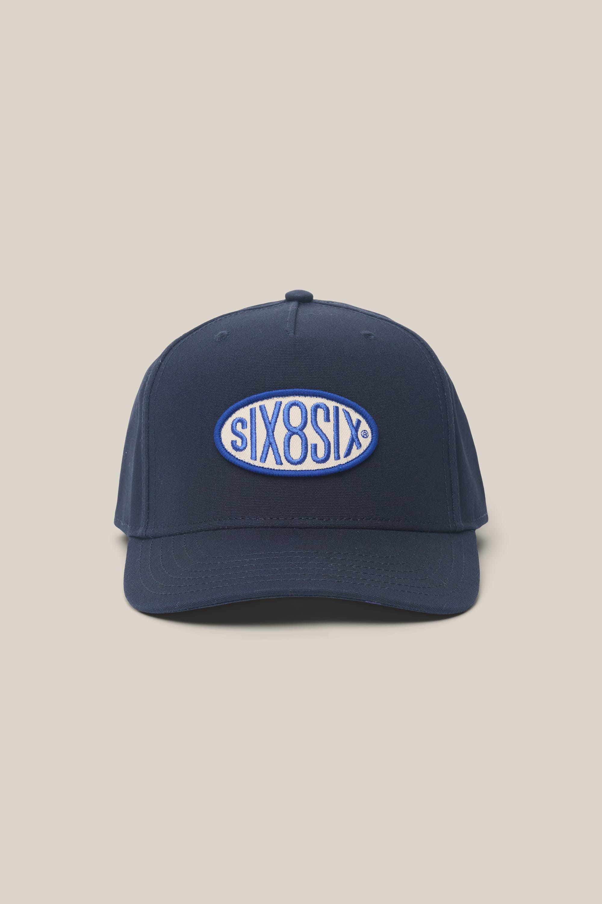 The 686 High-Pro 92 Structured 5 Panel Hat by 686 is a navy men's polyester-cotton cap with a curved brim and a blue/white oval patch reading SIX8SIX, shown against a plain beige background.