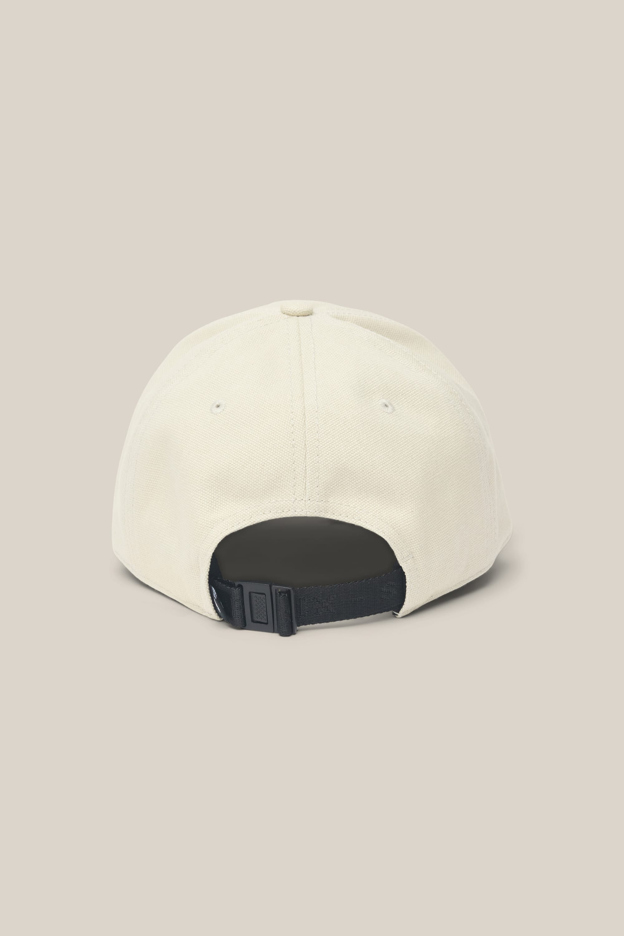 The 686 Low-Pro Unwork Unstructured 6 Panel Hat by 686 is displayed from the back, showcasing its beige polyester cotton construction, black adjustable strap, and metal clasp against a plain light background.