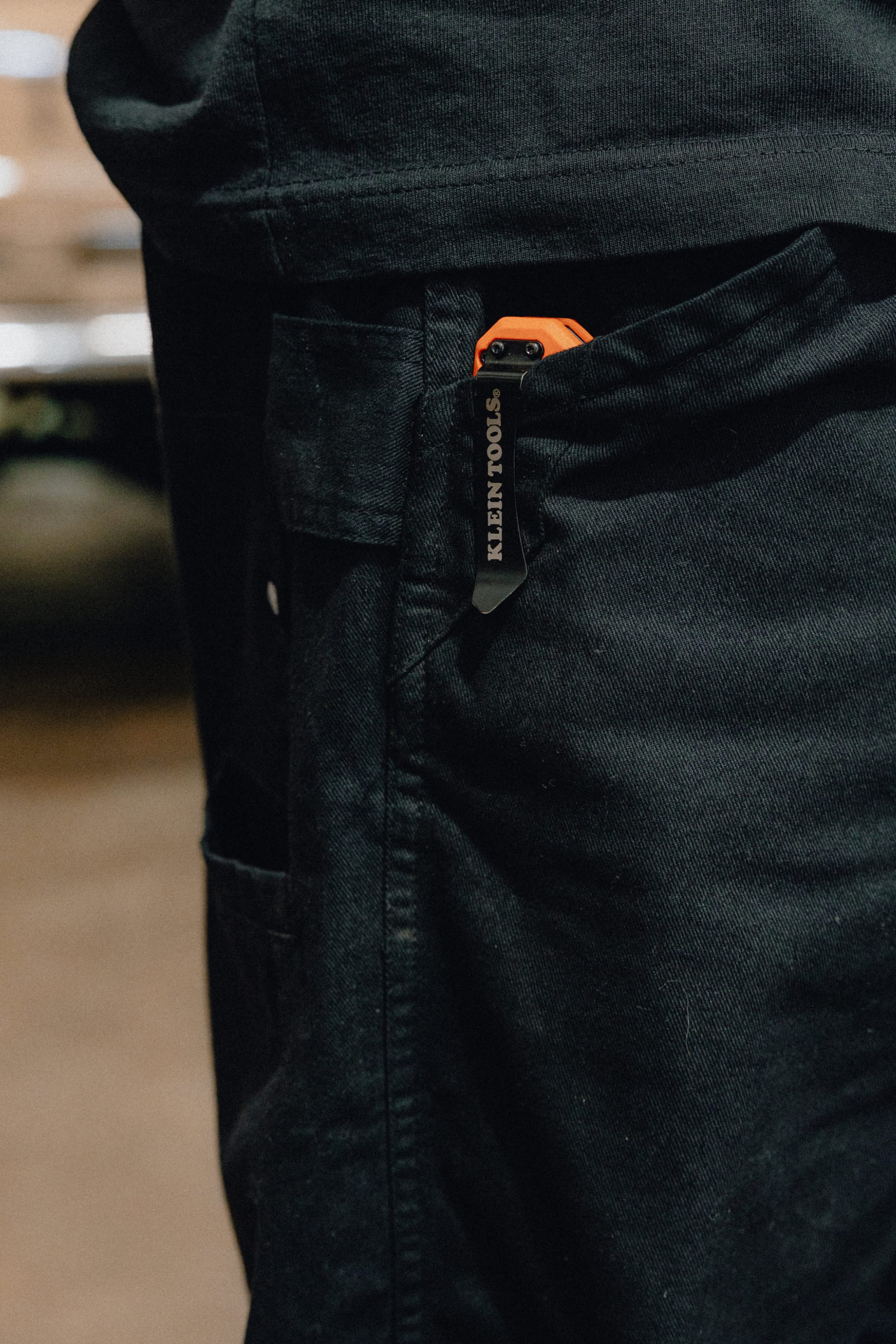 A Klein Tools utility knife with an orange handle is clipped to the front pocket of the 686 Men's Unwork® Tradesman Pant - Relaxed Fit. The tool’s brand name is visible on the clip.