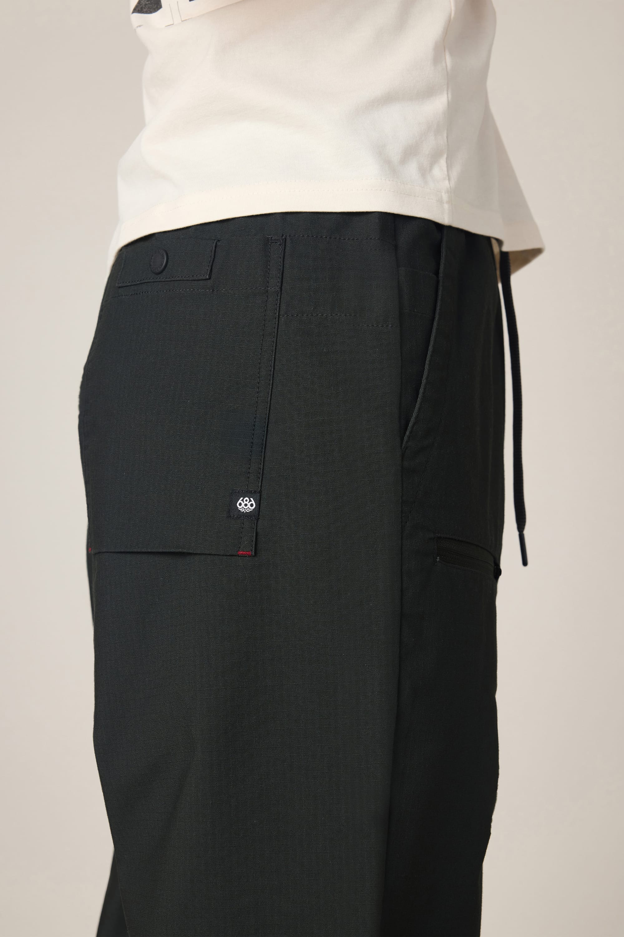 A person is shown from the waist down, focusing on the side pocket details of the 686 Men's Free Loader Pant - Loose Fit, highlighting the sleek design characteristic of this spandex woven pant by 686.