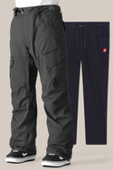 The 686 Men's SMARTY® 3-in-1 Cargo Pant in black, featuring zippered pockets, reinforced knees, and a removable sweatpant liner, is displayed in front of navy blue drawstring sweatpants with side pockets against a plain background.