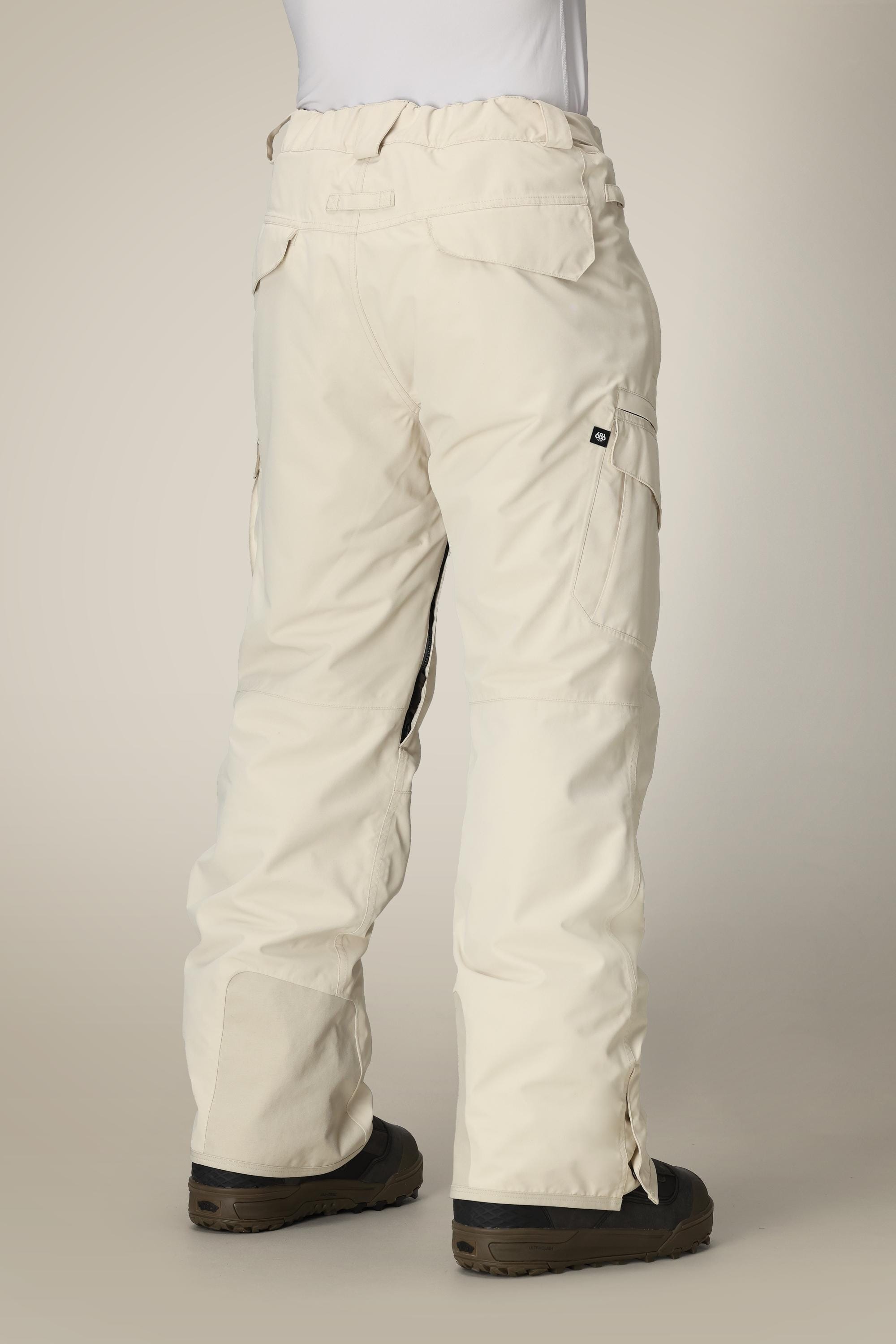 A person wearing the 686 Men’s SMARTY® 3-in-1 Cargo Pant in a cream color and black boots, photographed from the back against a neutral background.