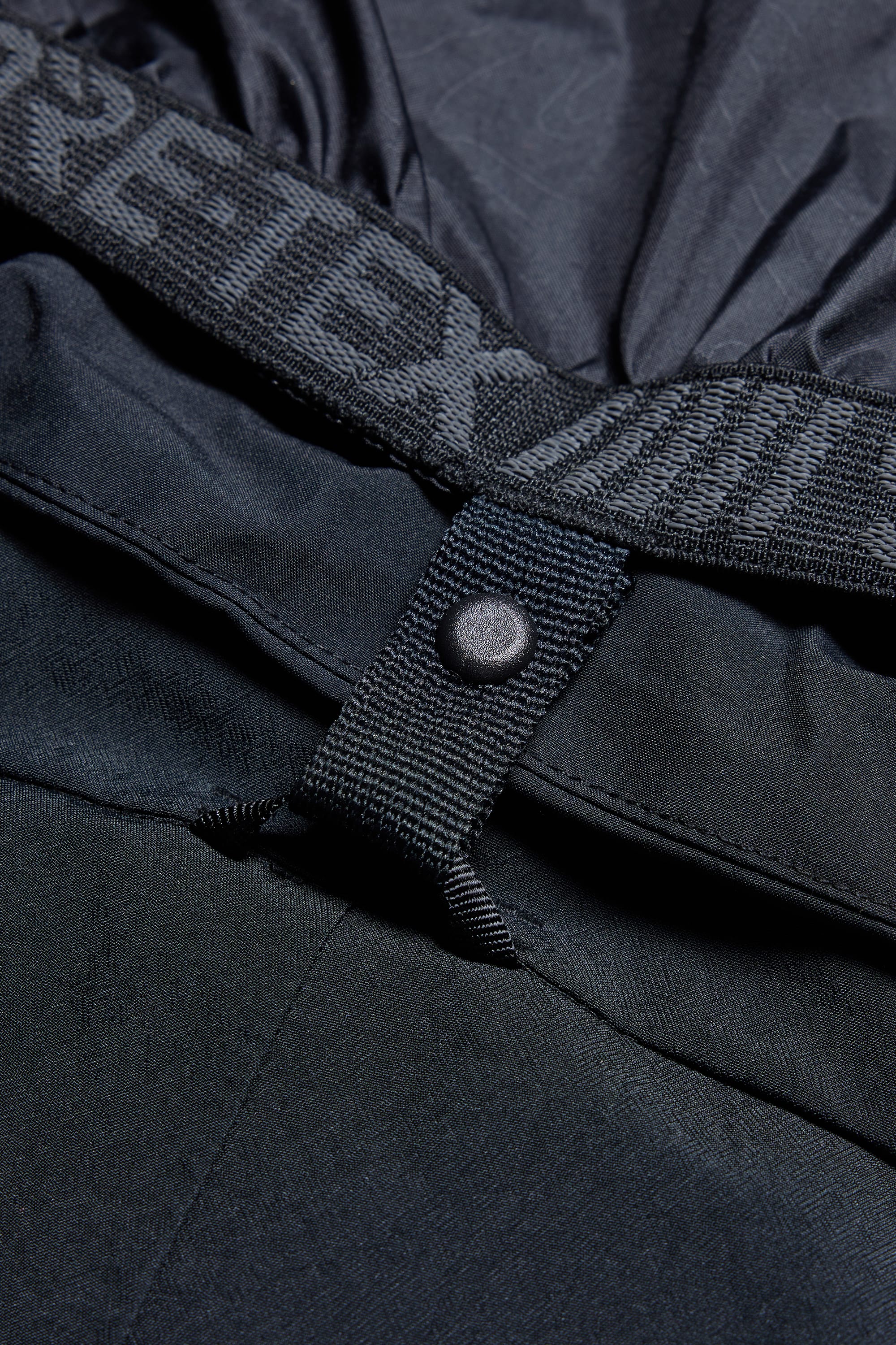 Close-up of the 686 Men's SMARTY® 3-in-1 Cargo Pant in black, showing a buttoned strap, elastic waistband with partial GORE-TEX branding, plus textured fabric. Offers three versatile wearing options for all conditions.
