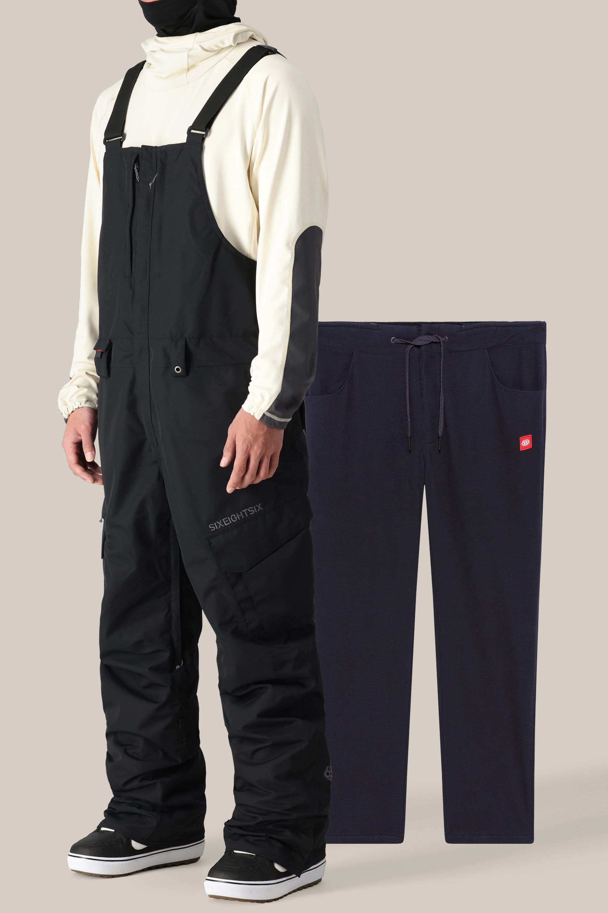 A person in a cream hoodie, black 686 Men's SMARTY® 3-in-1 Cargo Bib pants, black sneakers, and a black balaclava stands beside navy blue sweatpants displayed on a plain background.
