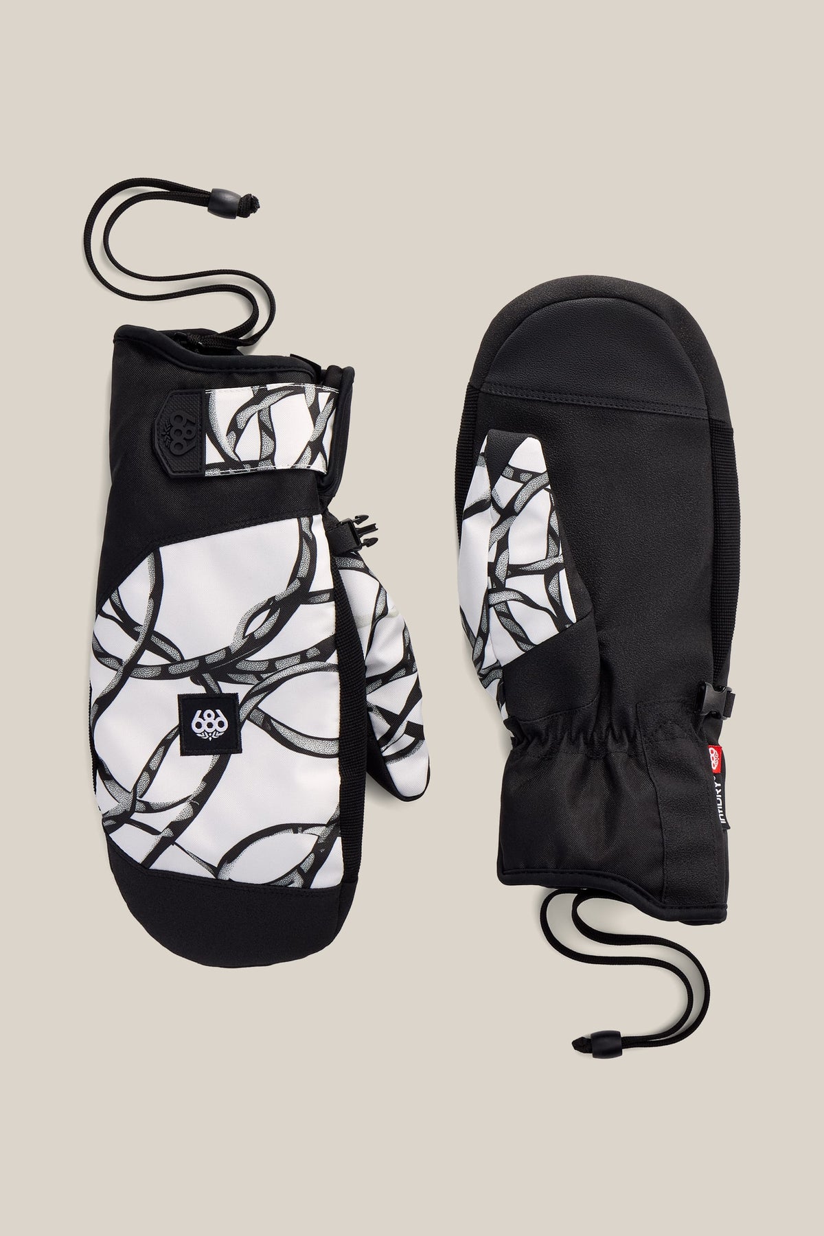 Two 686 Men’s Primer Mitts with black palms and a black-and-white chain pattern on the tops, featuring adjustable wrist straps and attached cords, are displayed on a neutral beige background.