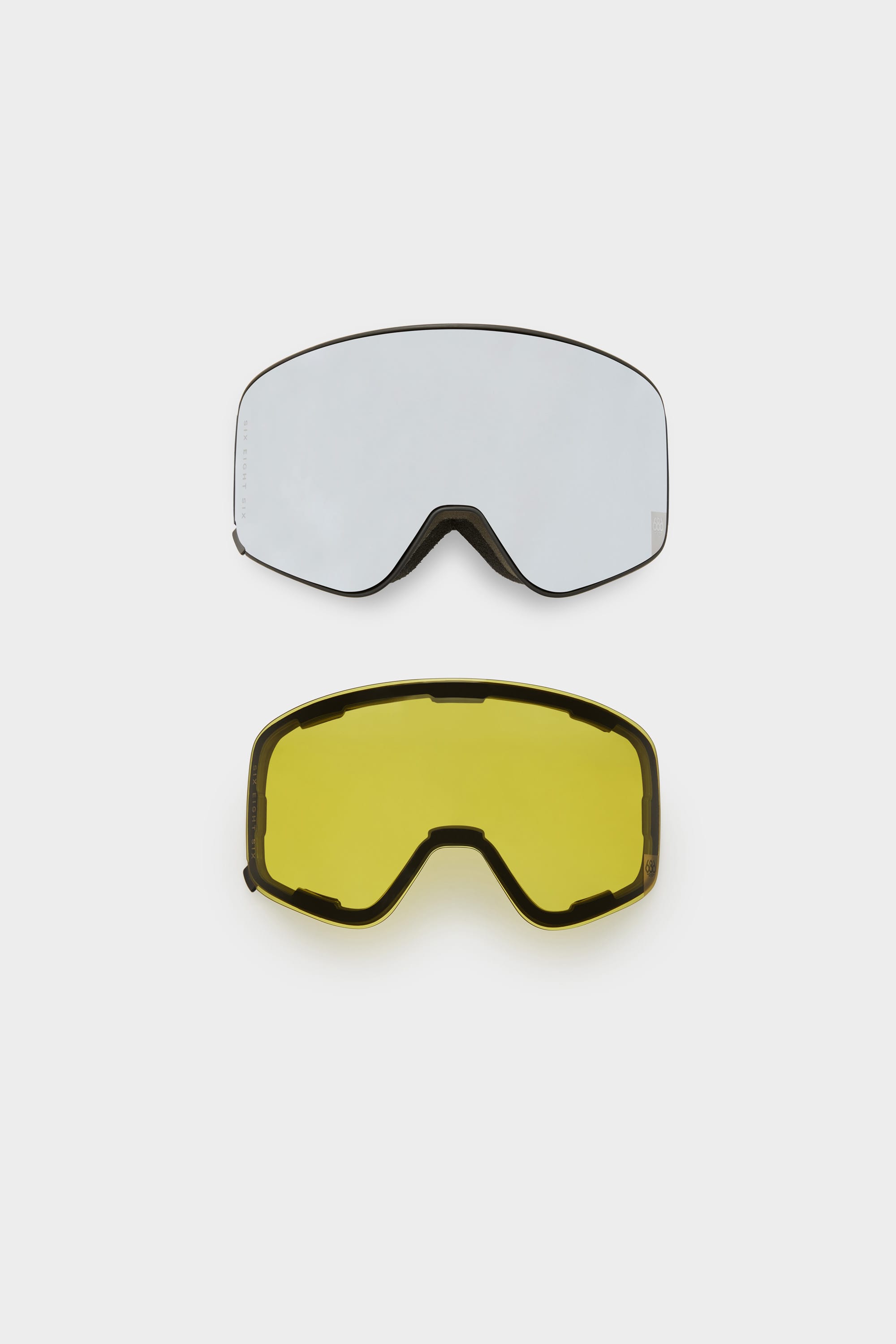 The 686 SMARTY® Magnetic Goggle by 686 is shown with two interchangeable magnetic lenses—clear on top and yellow on the bottom—displayed vertically against a white background, highlighting its minimalist design.