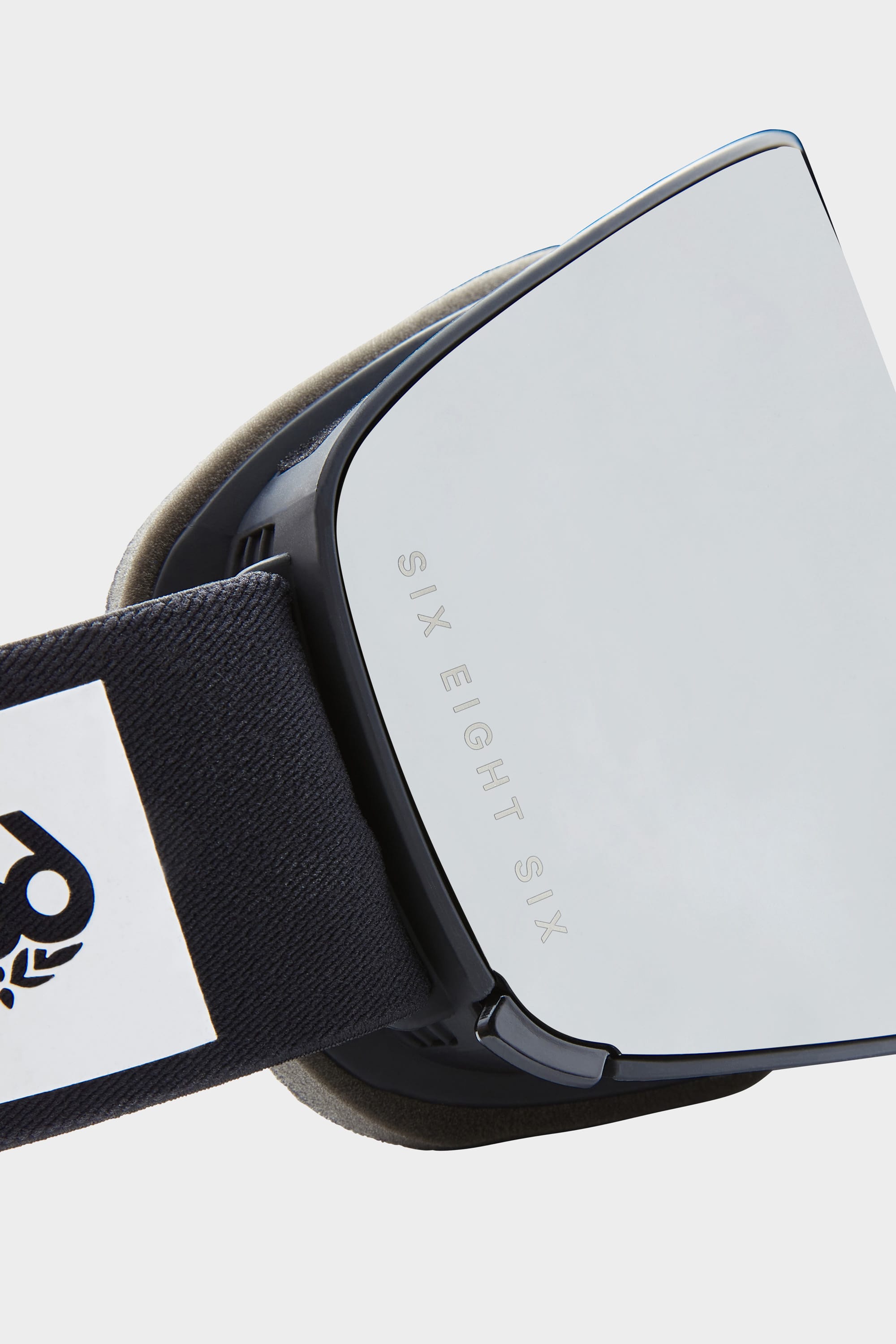 Close-up of the 686 SMARTY® Magnetic Goggle with reflective magnetic lenses, 686 branding etched on the lens, and a black strap featuring a white and black 686 logo.