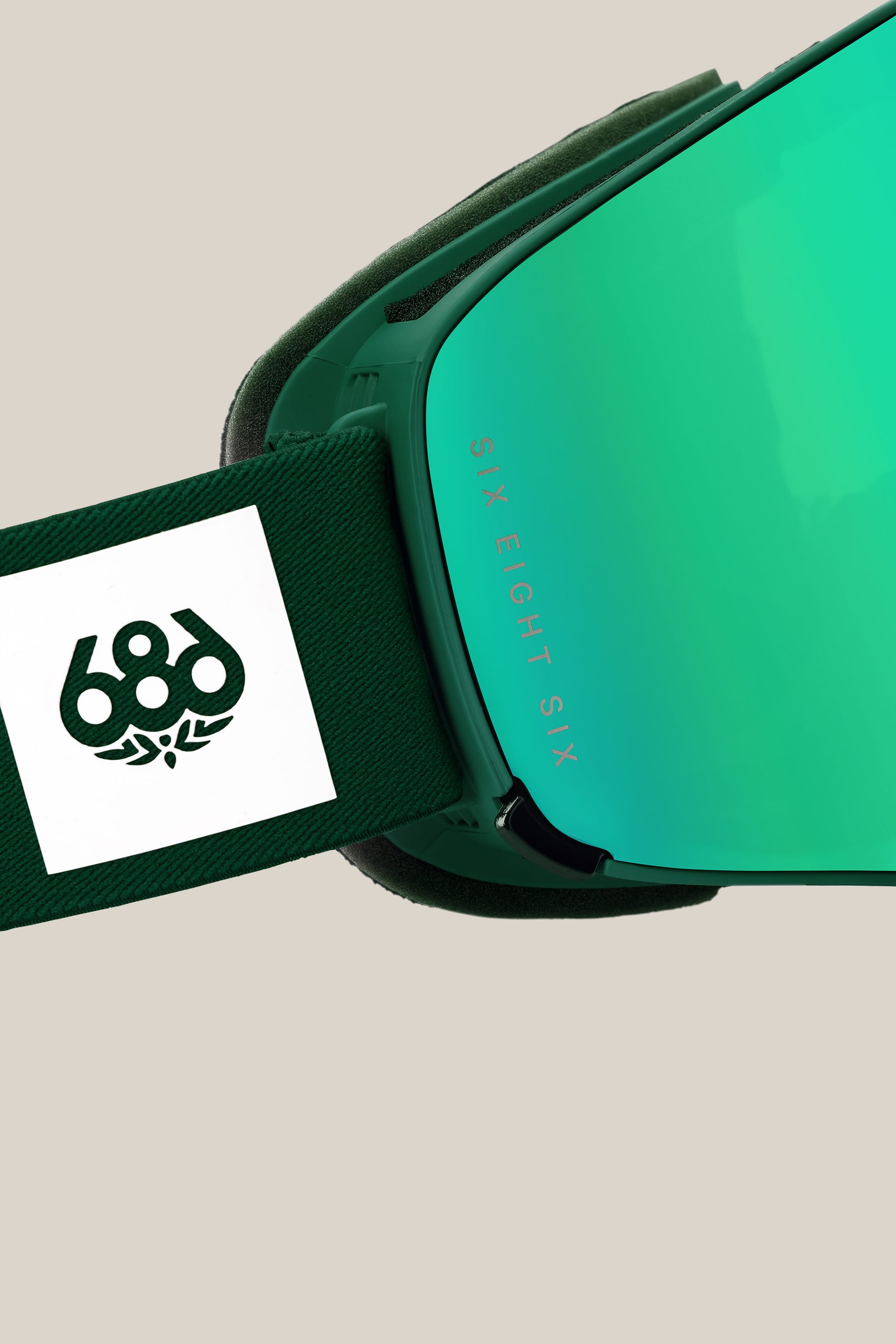 Close-up of the 686 SMARTY¨ Magnetic Goggle, featuring a green magnetic reflective lens, dark green strap with a white rectangular patch, and visible "686" branding.