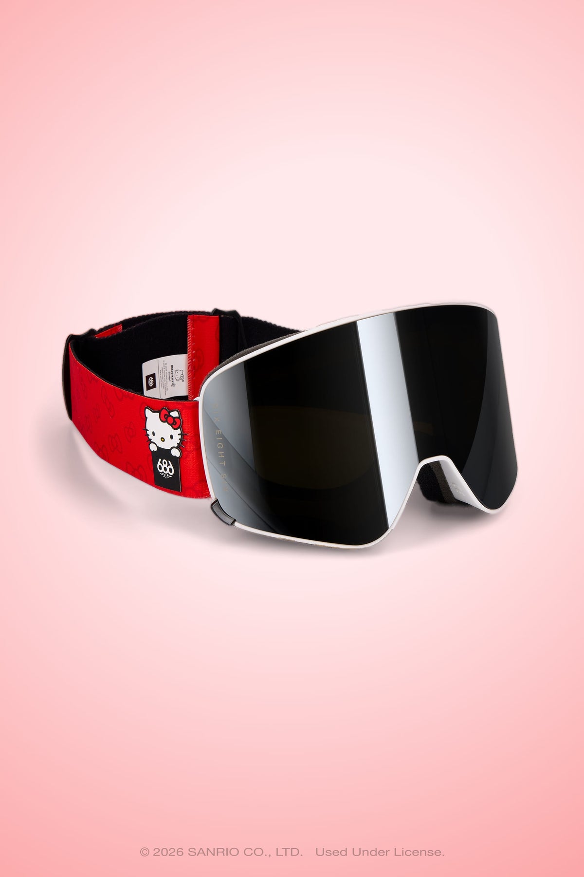 The 686 SMARTY® Magnetic Goggle by 686 features red and black magnetic lenses, a Hello Kitty design on the strap, and provides full-lens vision, shown against a pink gradient background.