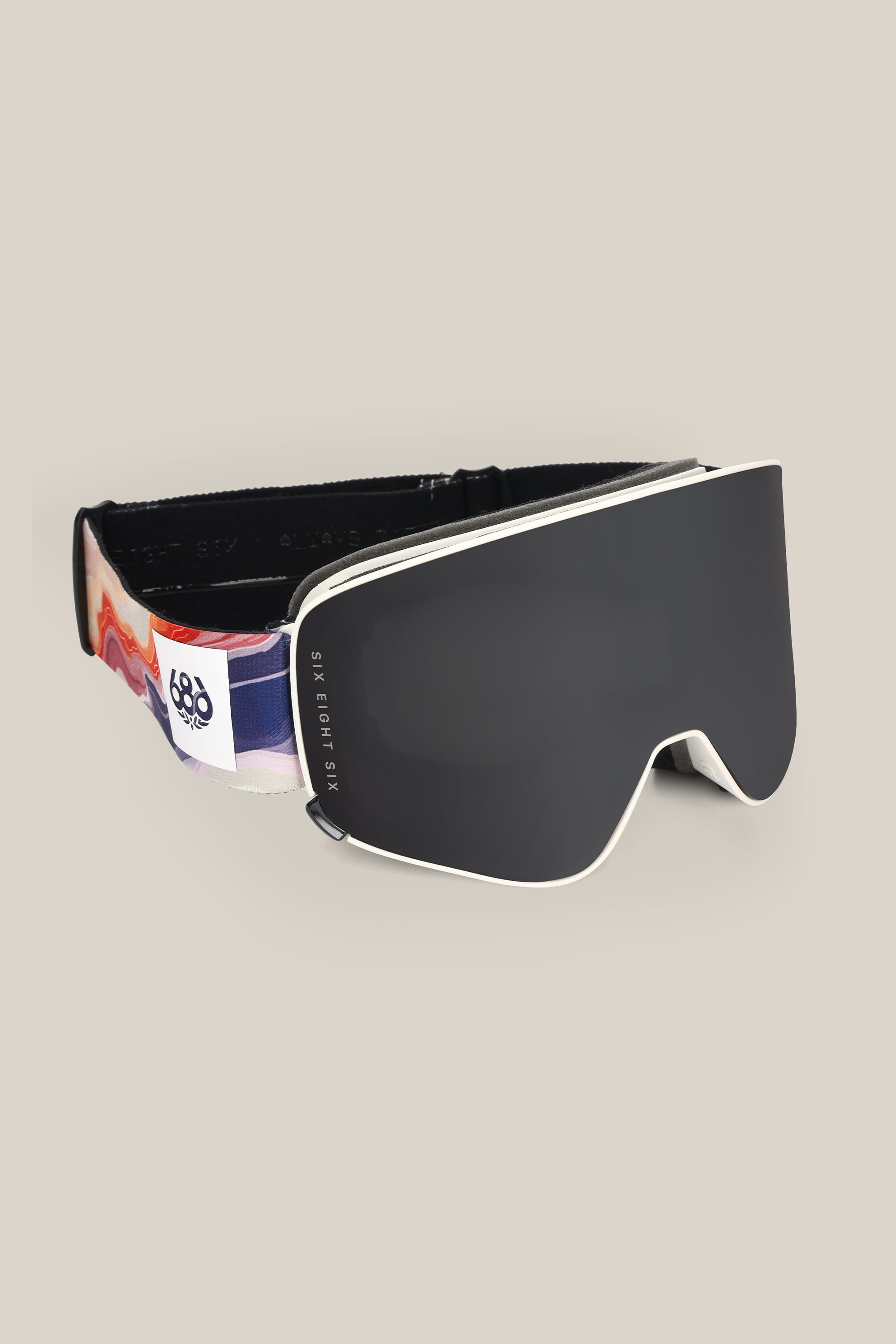 The 686 SMARTY® Magnetic Goggle by 686 features a sleek black minimalist design, a wide frameless lens, and a patterned strap with a white logo tag, shown against a plain beige background.