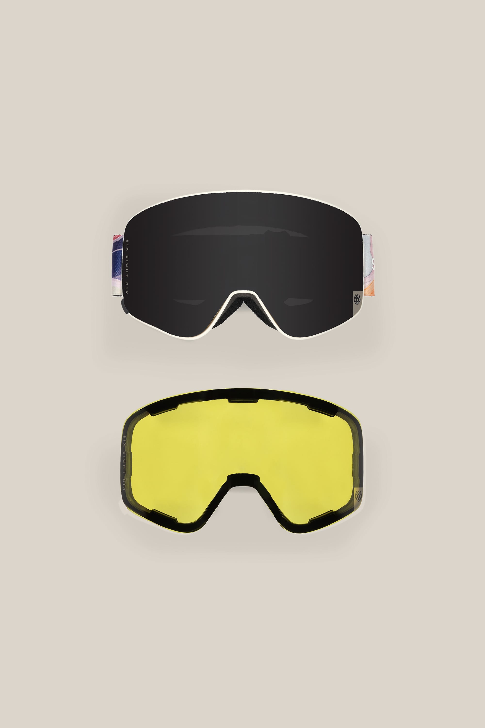Two 686 SMARTY™ Magnetic Goggles are shown on a beige background. The top has a dark, reflective lens; the bottom a yellow-tinted lens. Both face forward and offer interchangeable lenses for versatile performance.