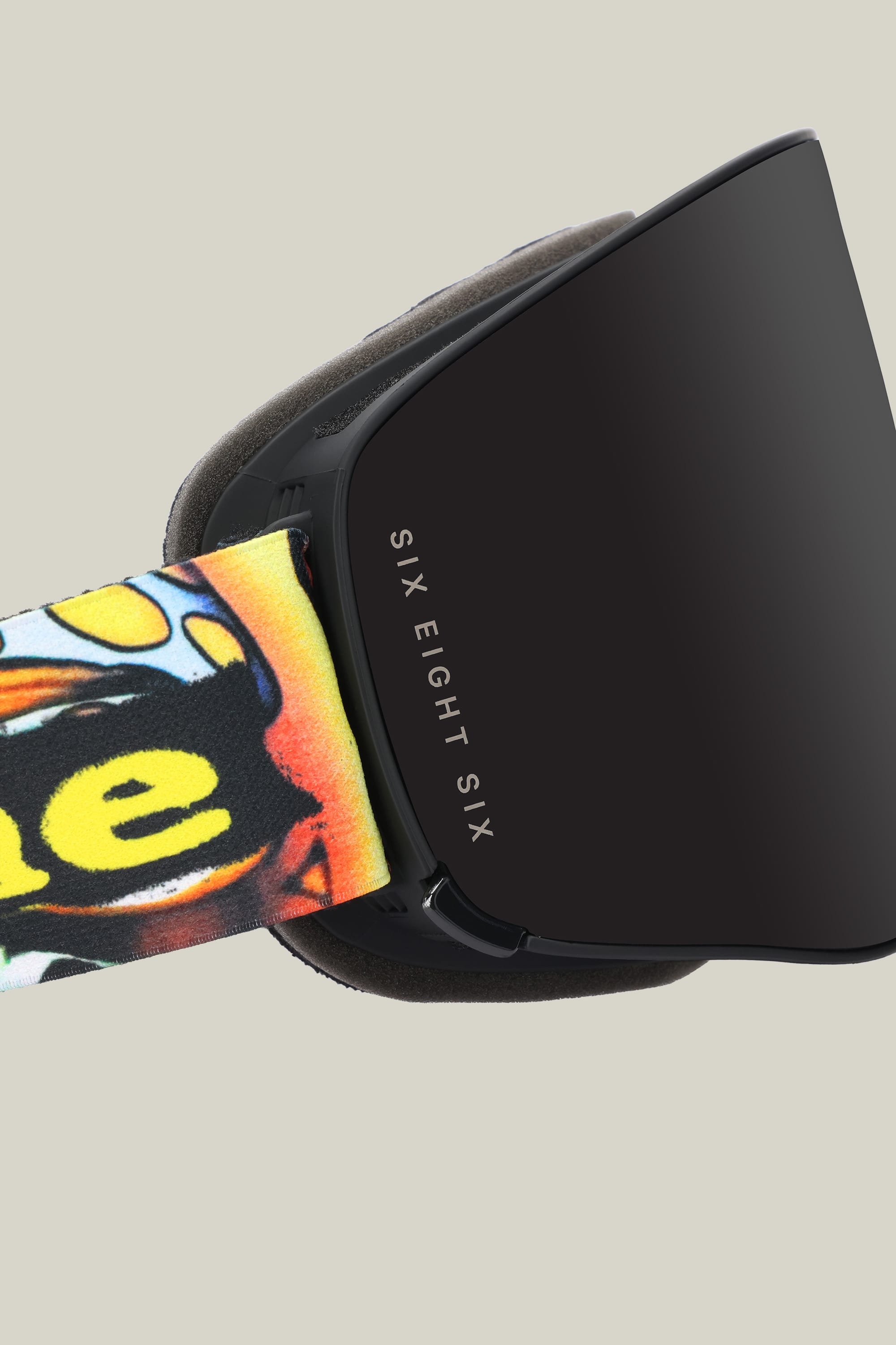 Close-up of the 686 SMARTY® Magnetic Goggle featuring "686" branding on the lens frame and a vibrant strap with bold yellow and black graphics, set against a plain light background.