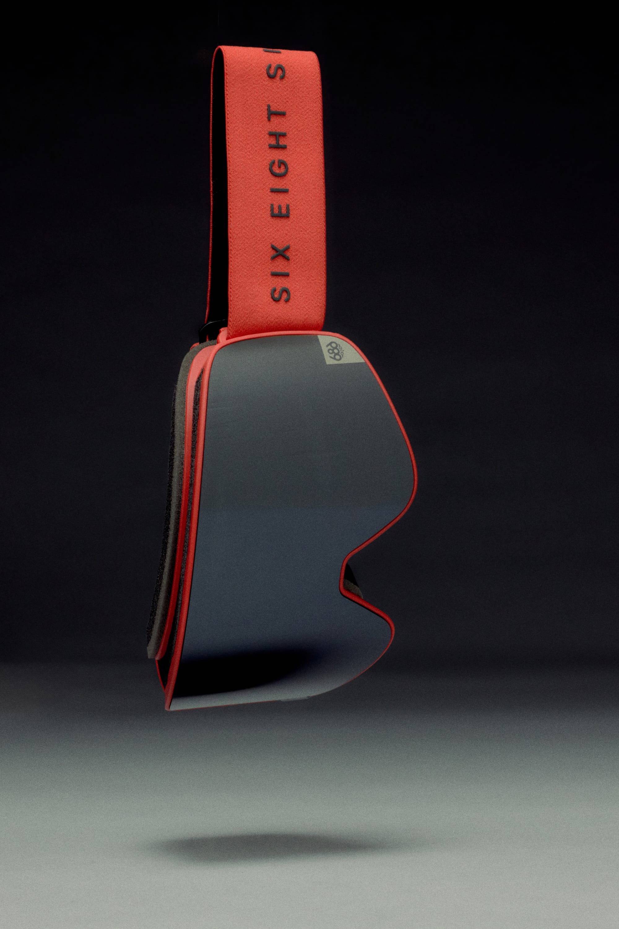 The 686 SMARTY® Magnetic Goggle by 686 features mirrored magnetic lenses, a red frame and strap, and “SIX EIGHT SIX” in bold black letters, shown suspended against a dark gradient background.