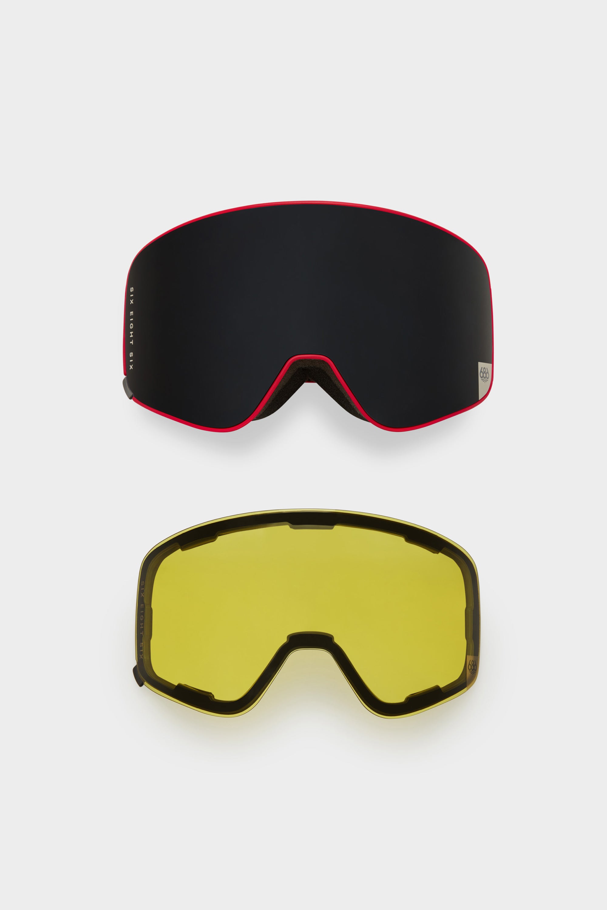 Two interchangeable lenses for the 686 SMARTY¨ Magnetic Goggle by 686 are displayed on a white background: one with a dark lens and red trim, the other with a yellow lens and black trim.