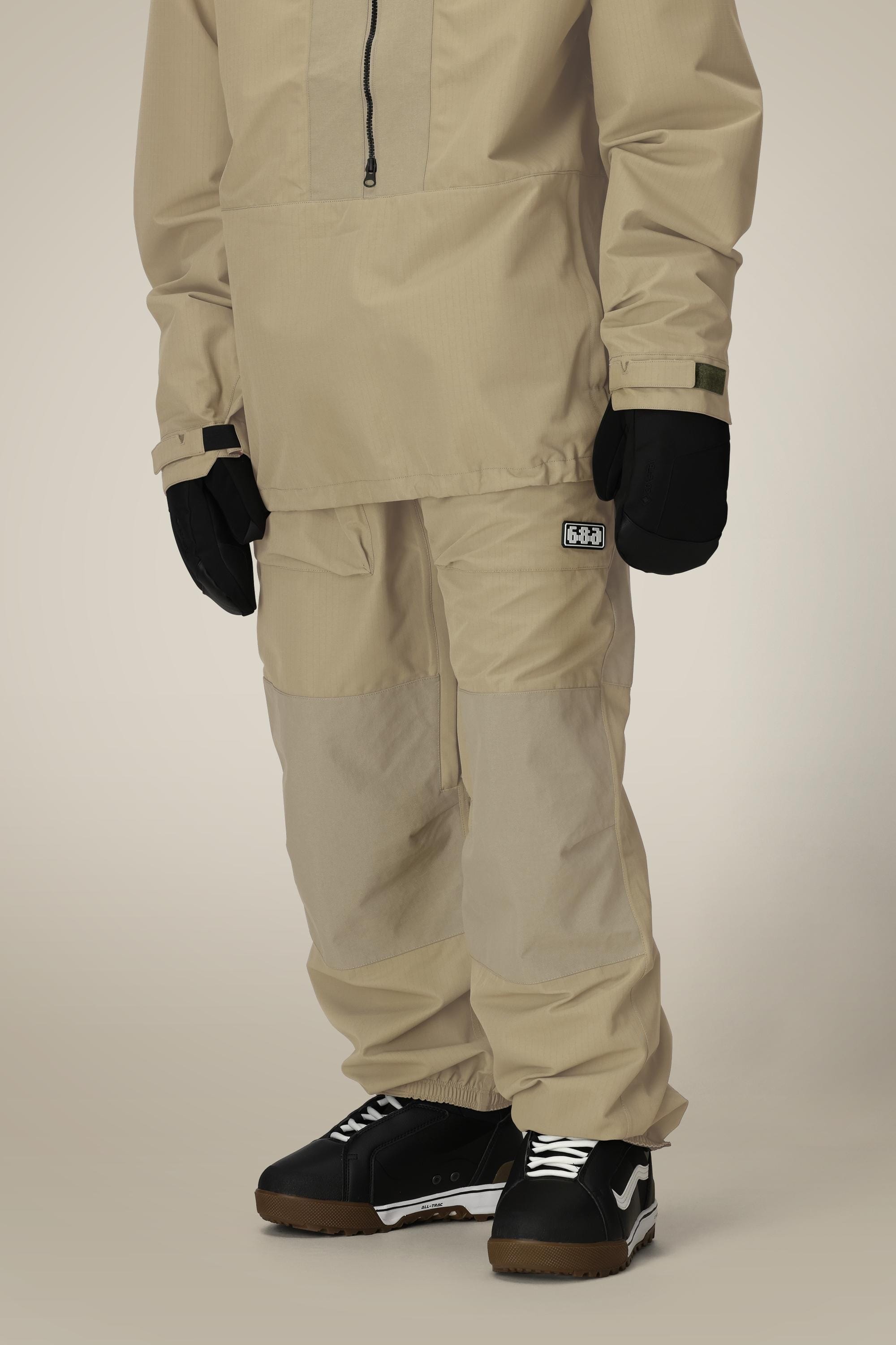A person wearing 686 Ghost™ 2.5L Pant, black gloves, and black sneakers with white accents stands against a neutral background. Only the lower half of the body is visible.
