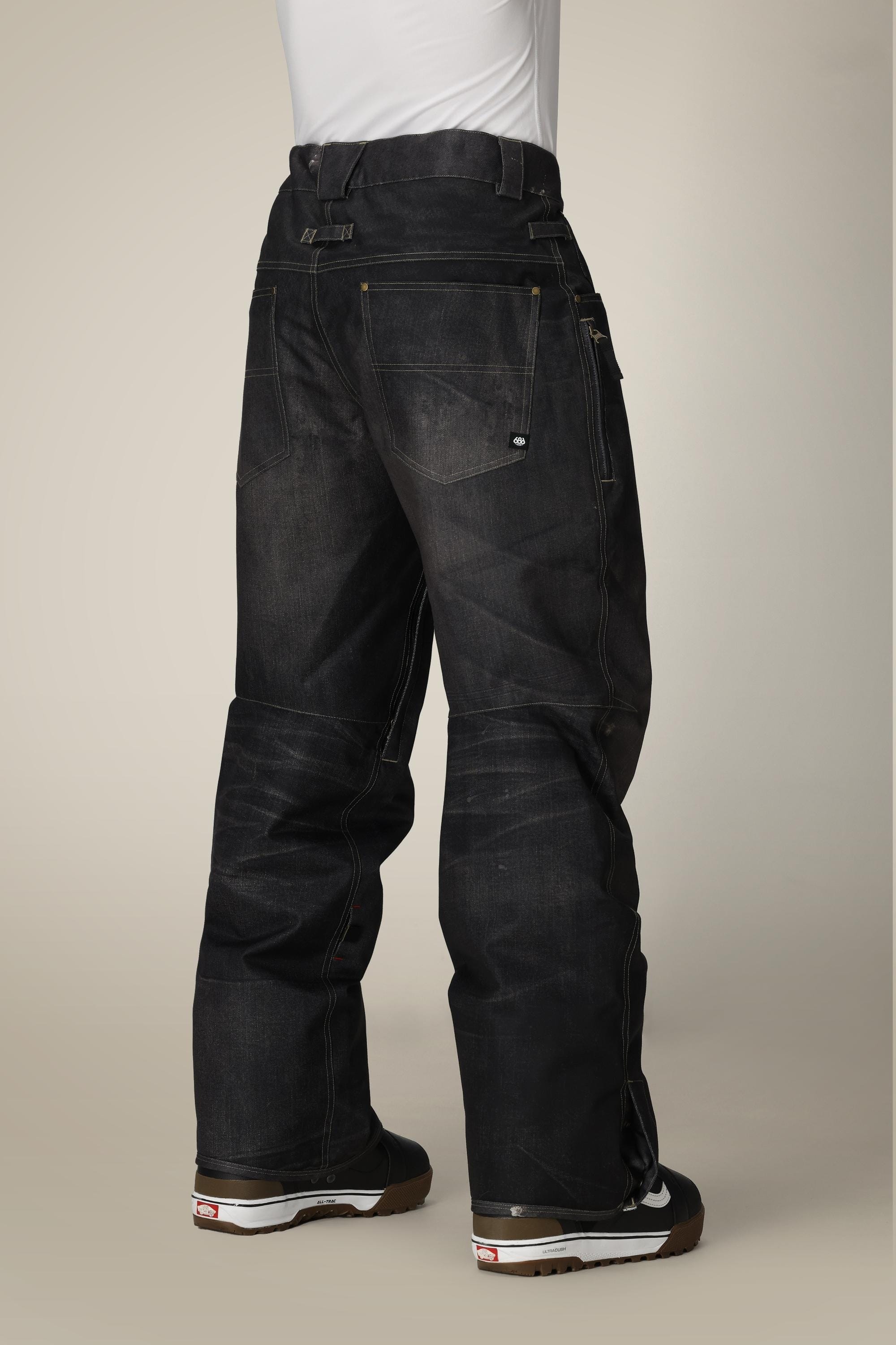A person is shown from the back against a neutral background, wearing a white shirt, 686 Men's Deconstructed™ Denim Pant by 686 with visible seams and pockets, and black sneakers with white soles.