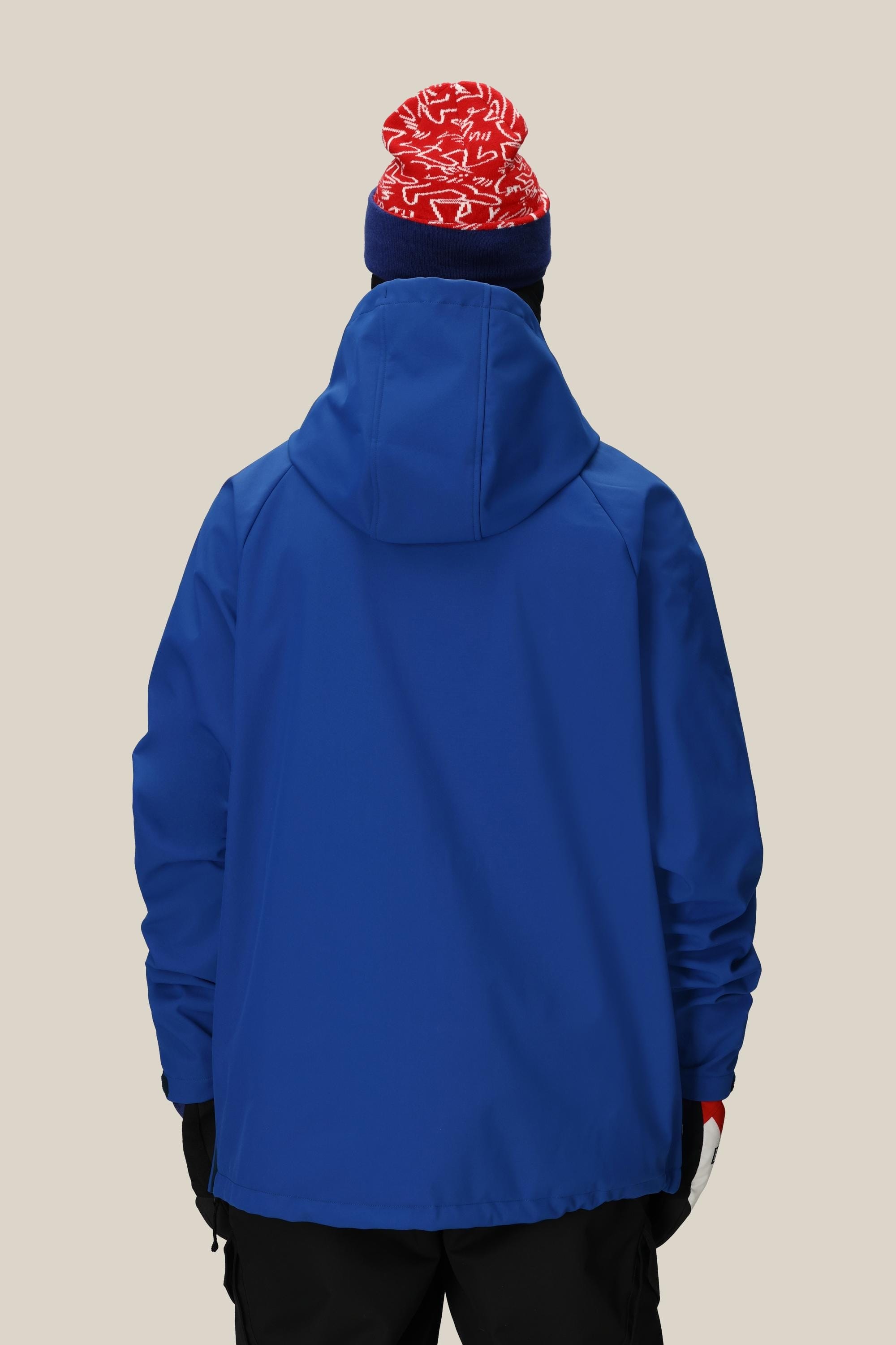 A person is shown from the back against a beige background wearing the 686 Mens Waterproof Hoody in blue, paired with black pants, black gloves, and a red knit hat with white patterns.