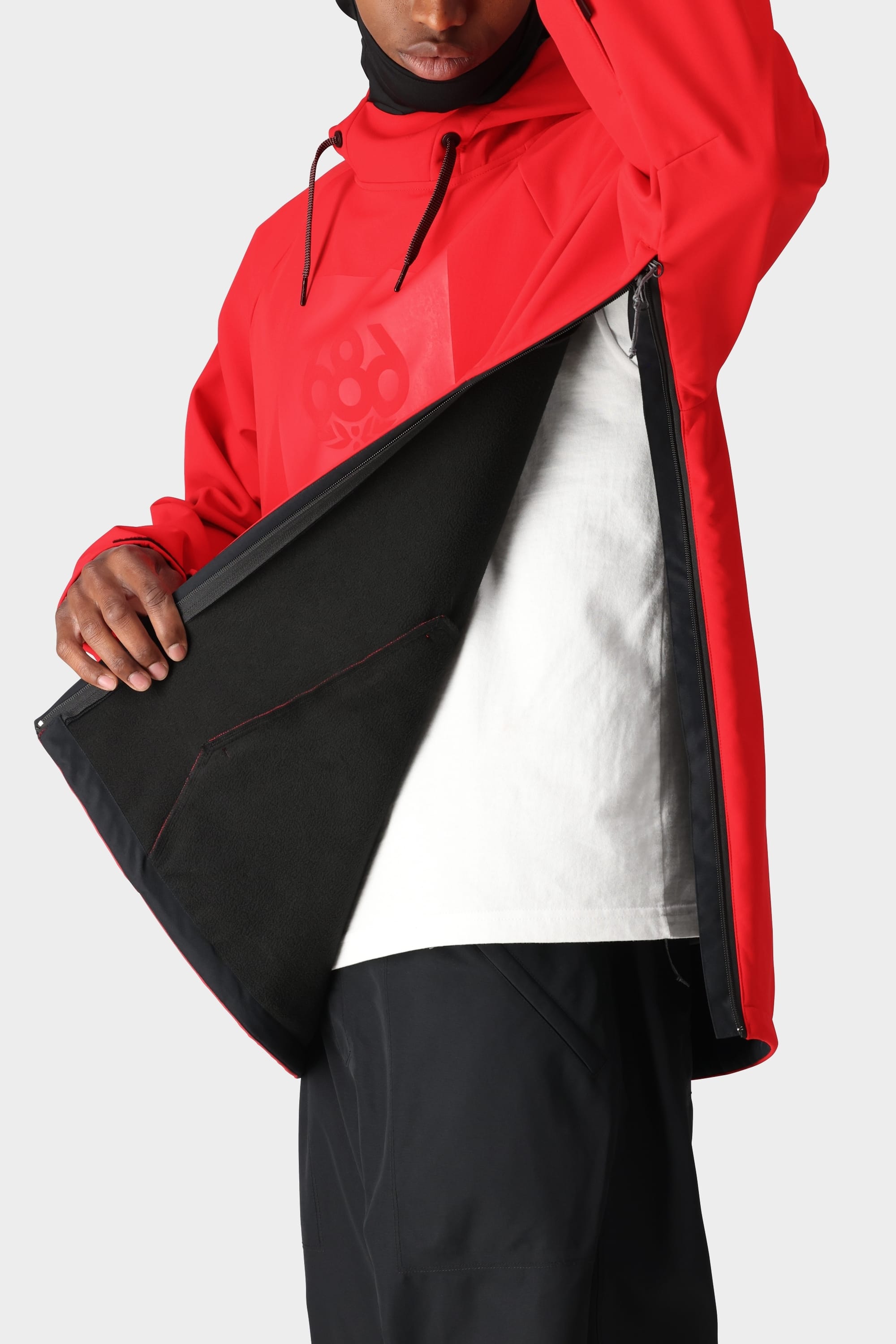A person is wearing the 686 Men’s Waterproof Hoody by 686 with the side zipper open, showing a white shirt underneath and the black inner lining of the hoody. The person’s face is partially out of frame.