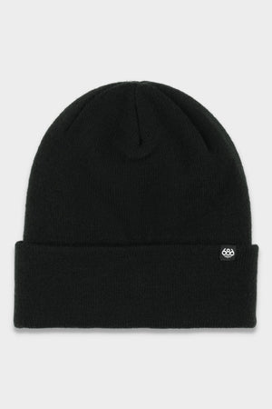 The 686 Standard Roll Up Beanie by 686 is a plain black knit hat with a folded brim and a small white logo tag on the front, set against a light gray background.