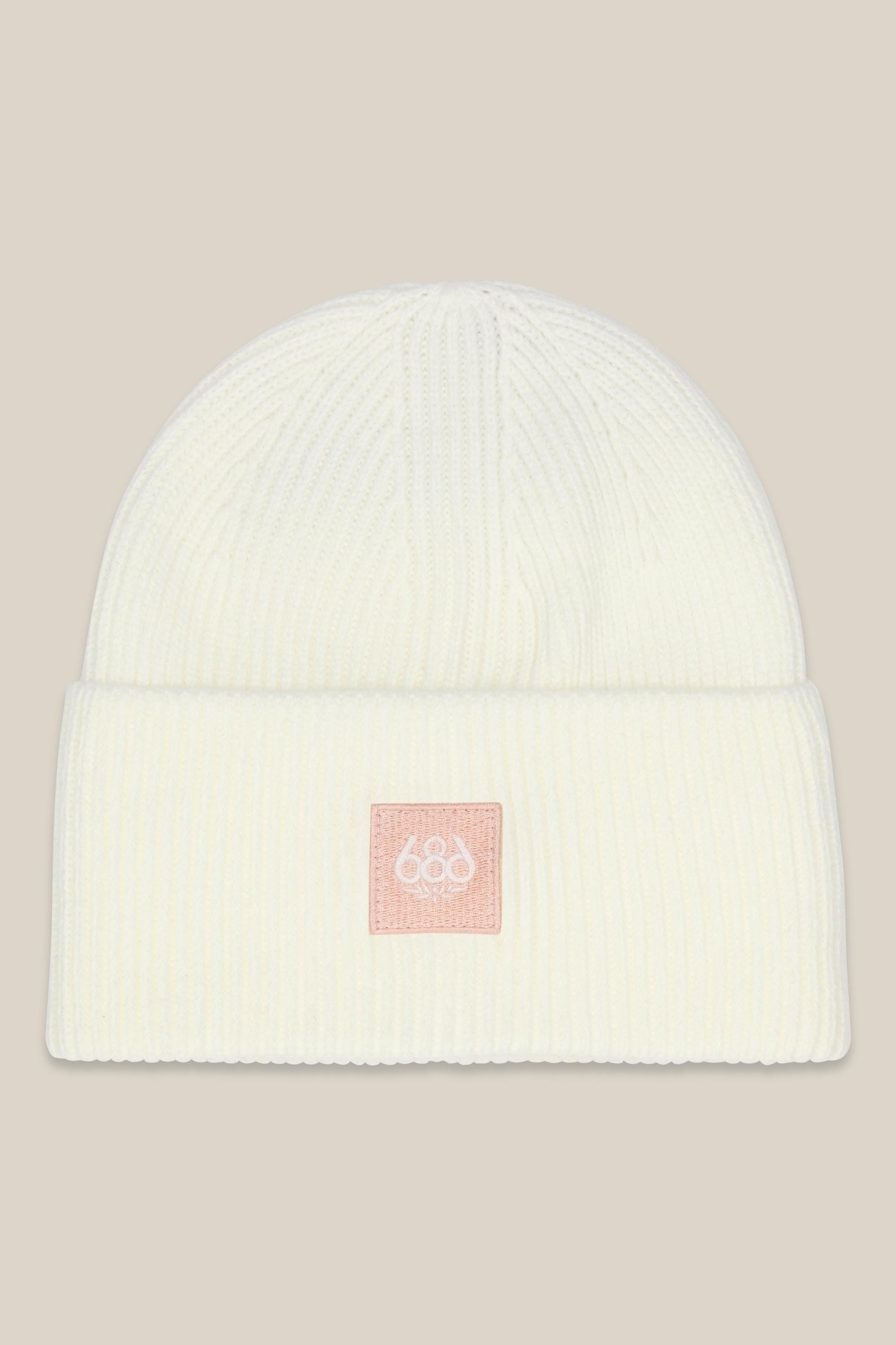 The 686 Big Cuff Beanie by 686 is a white ribbed knit hat with a folded brim and a small pink embroidered 686 patch on the front. Stylish autumn headwear, shown against a solid beige background.