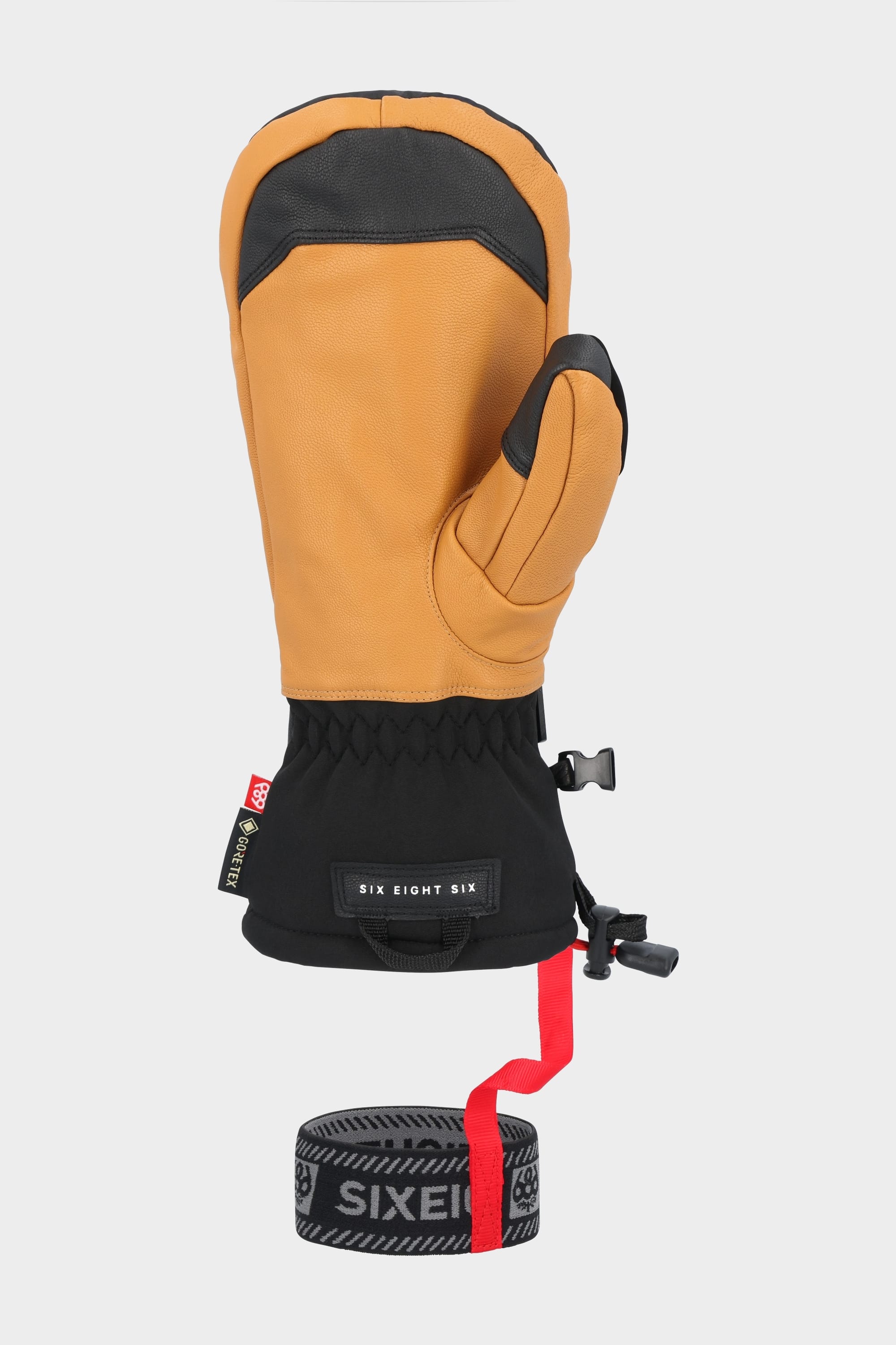 The 686 Men’s GORE-TEX Leather Linear™ Mitt features a tan and black design, leather palm, adjustable wrist strap, drawstring closure, separate thumb section, durable insulated build—ideal for cold weather activities.