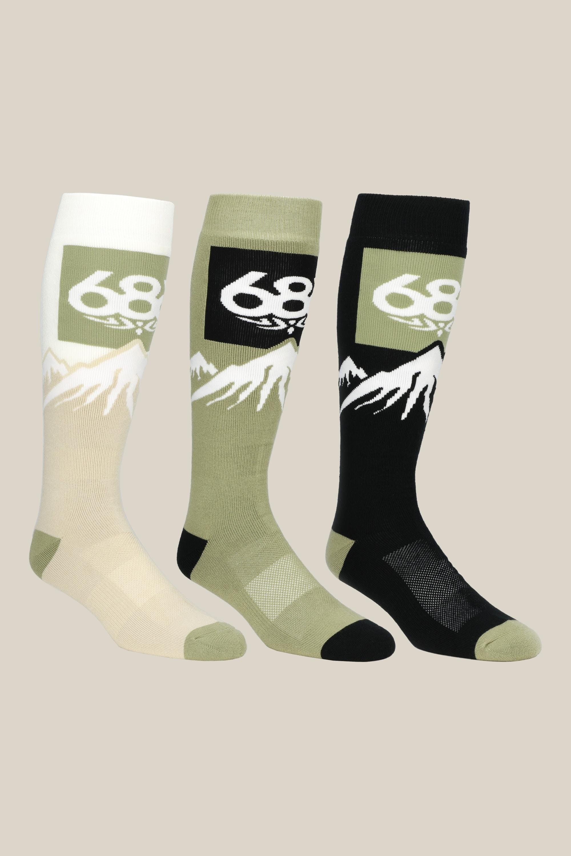 The 686 Mens Snow Caps Sock (3-Pack) includes comfy knee-high socks in cream, olive green, and black, each with a white mountain graphic and 686 inside a green rectangle by the top.