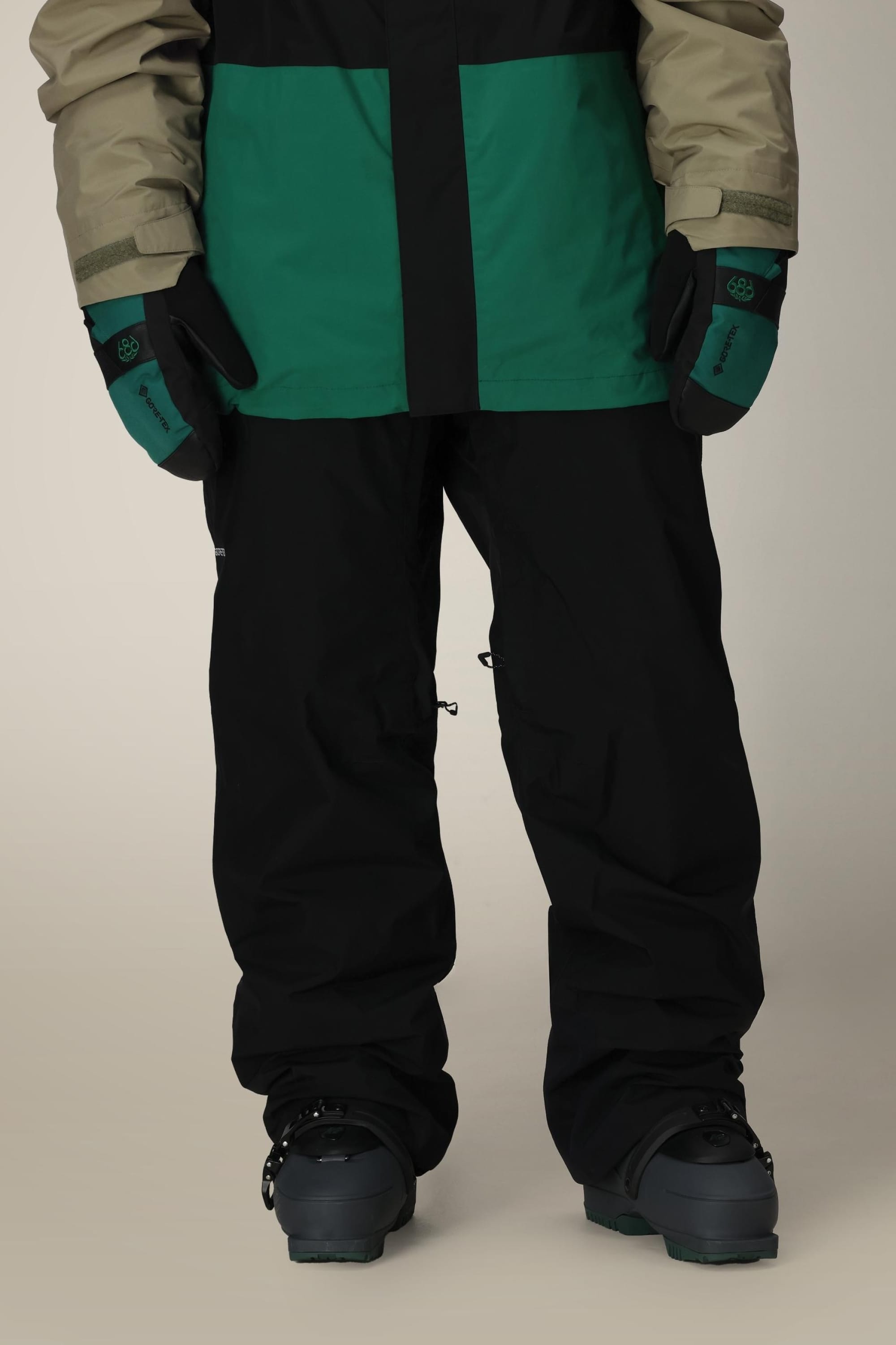 A person wearing 686 Mens GORE-TEX Core Shell Pant in black and a green jacket.