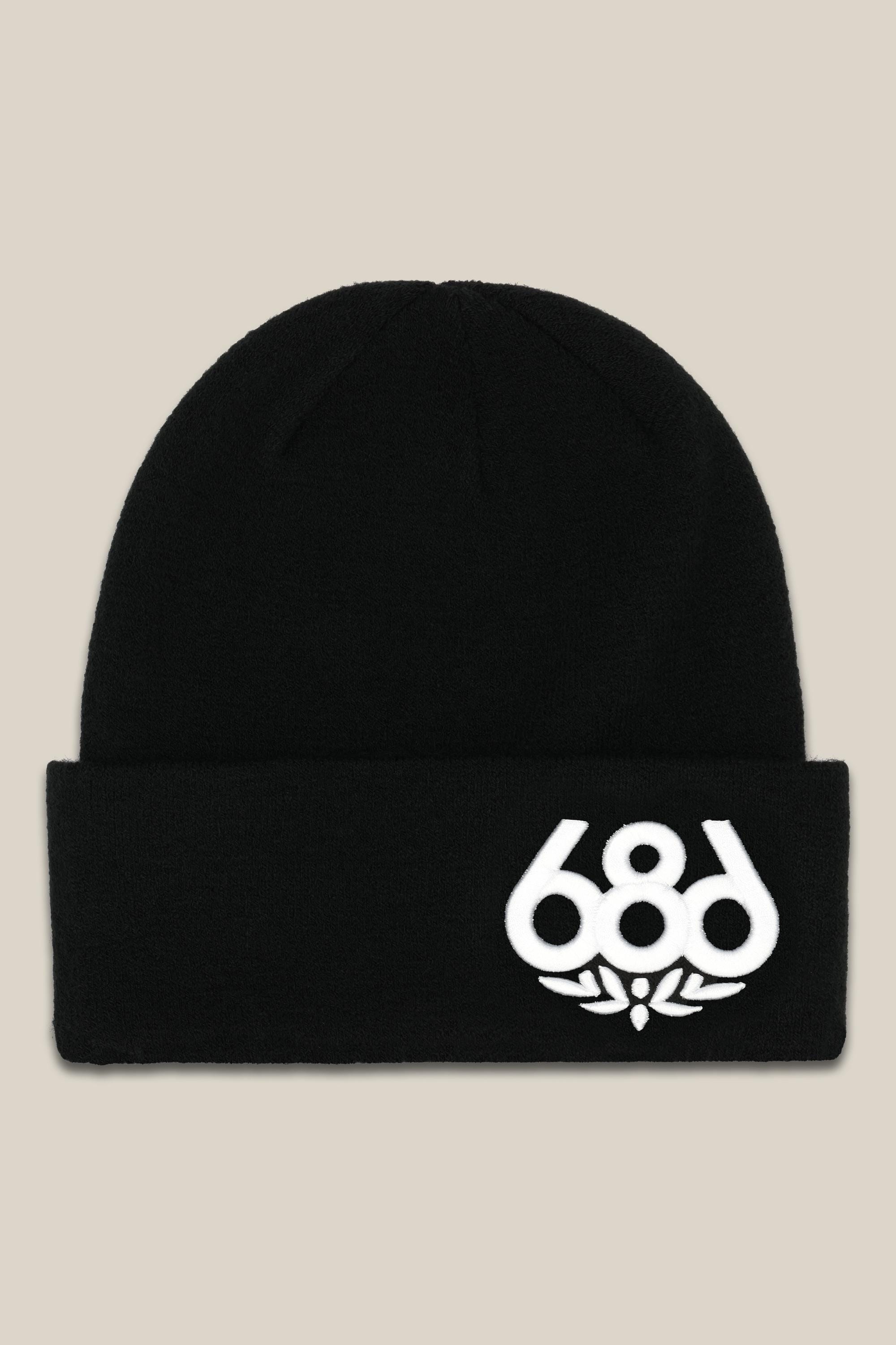 The 686 Big Logo Embroidered Beanie by 686 is a black acrylic knit hat with a folded brim, featuring the white 686 logo and a leaf design on the front right side. Shown against a light beige background.