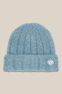 The 686 Womens Fuzzy Beanie is a light blue acrylic knit hat with a textured finish, folded brim, and small white 686 logo on the front right side. Set against a beige background, this versatile beanie is perfect for stylish women.