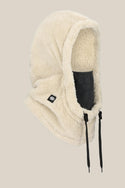 The 686 Tarmac Sherpa Hood by 686 is a beige, fluffy polyester knit balaclava with black drawstrings and a small black logo patch. This soft, warm unisex facemask covers most of the face, leaving only a dark fabric mask area exposed.