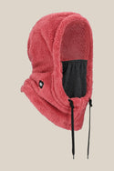 The 686 Tarmac Sherpa Hood by 686 is a pink, fluffy polyester knit balaclava with a hood, black face covering, black drawstrings, and a small black logo patch, shown on a plain beige background.