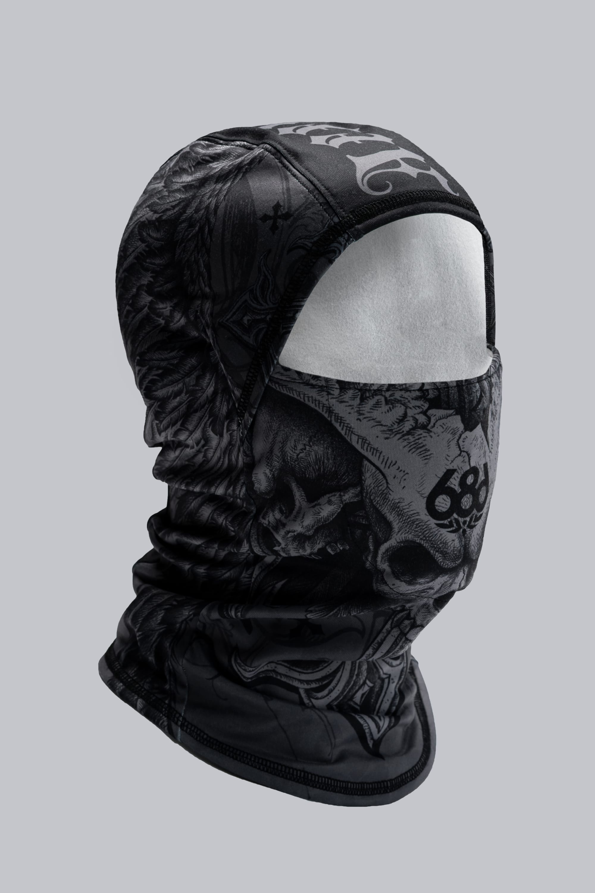 The 686 Affliction Hurra Hinged Balaclava by 686 is a black polyester facemask with a detailed skull and bone pattern, shown on a white mannequin head against a plain gray background.
