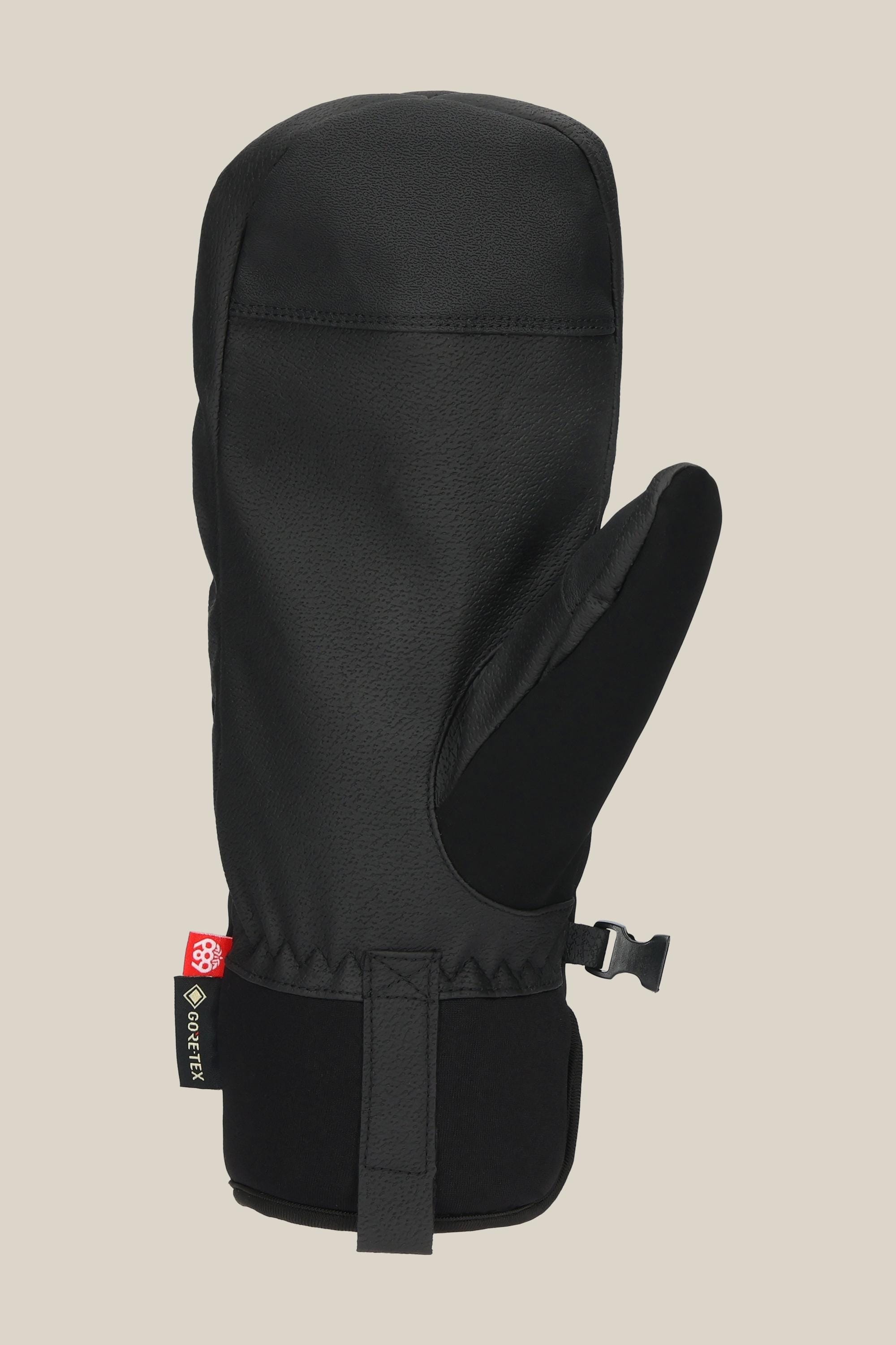 The 686 Men's GORE-TEX Linear™ Under Cuff Mitt, in black PU with a textured finish, features an adjustable wrist strap and a small red and white side tag, shown against a plain beige background.