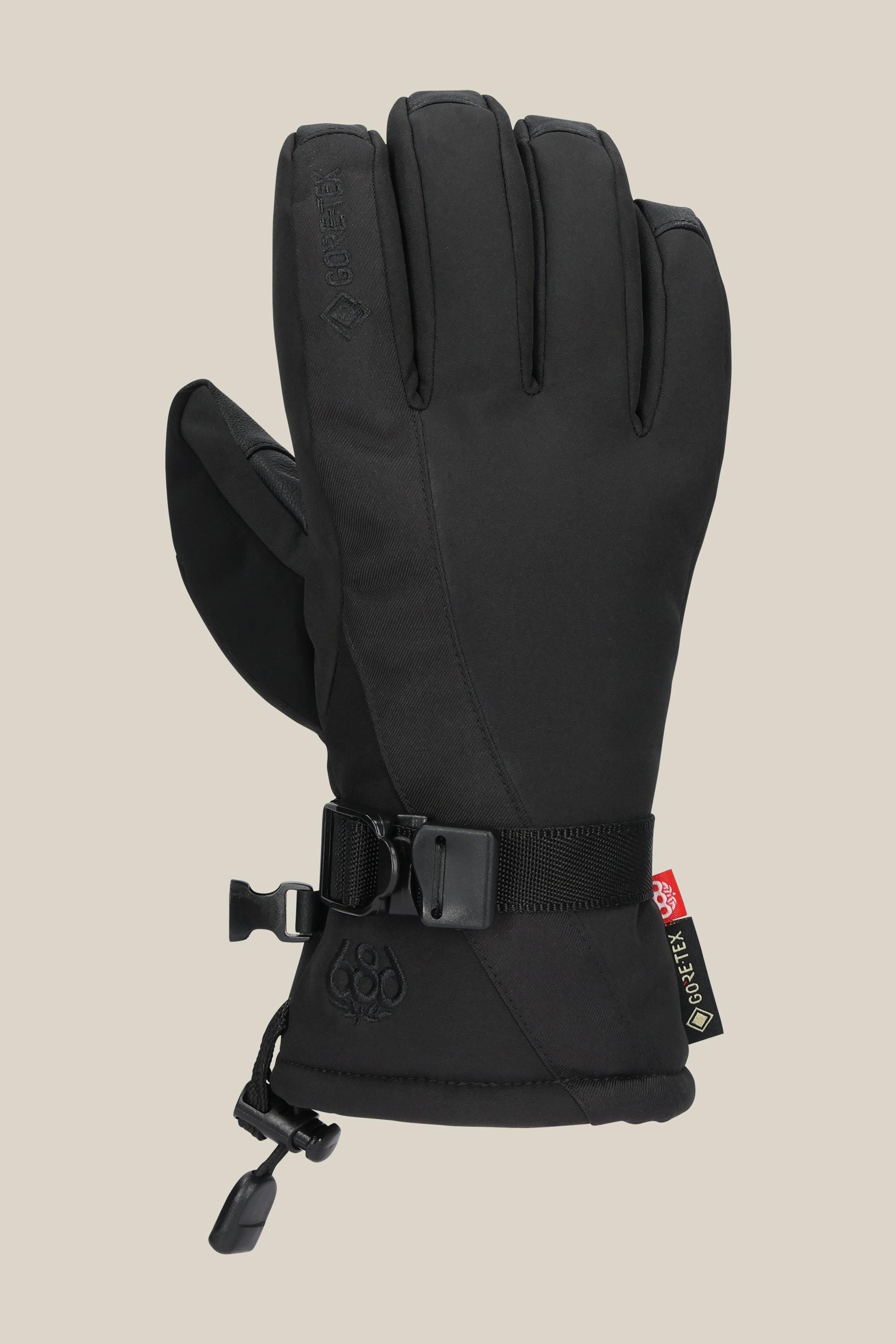 The 686 Women's GORE-TEX Linear™ Glove by 686 is a black insulated poly glove with an adjustable wrist strap, cinch cord cuff, and a red/yellow GORE-TEX tag, shown against a light beige background.