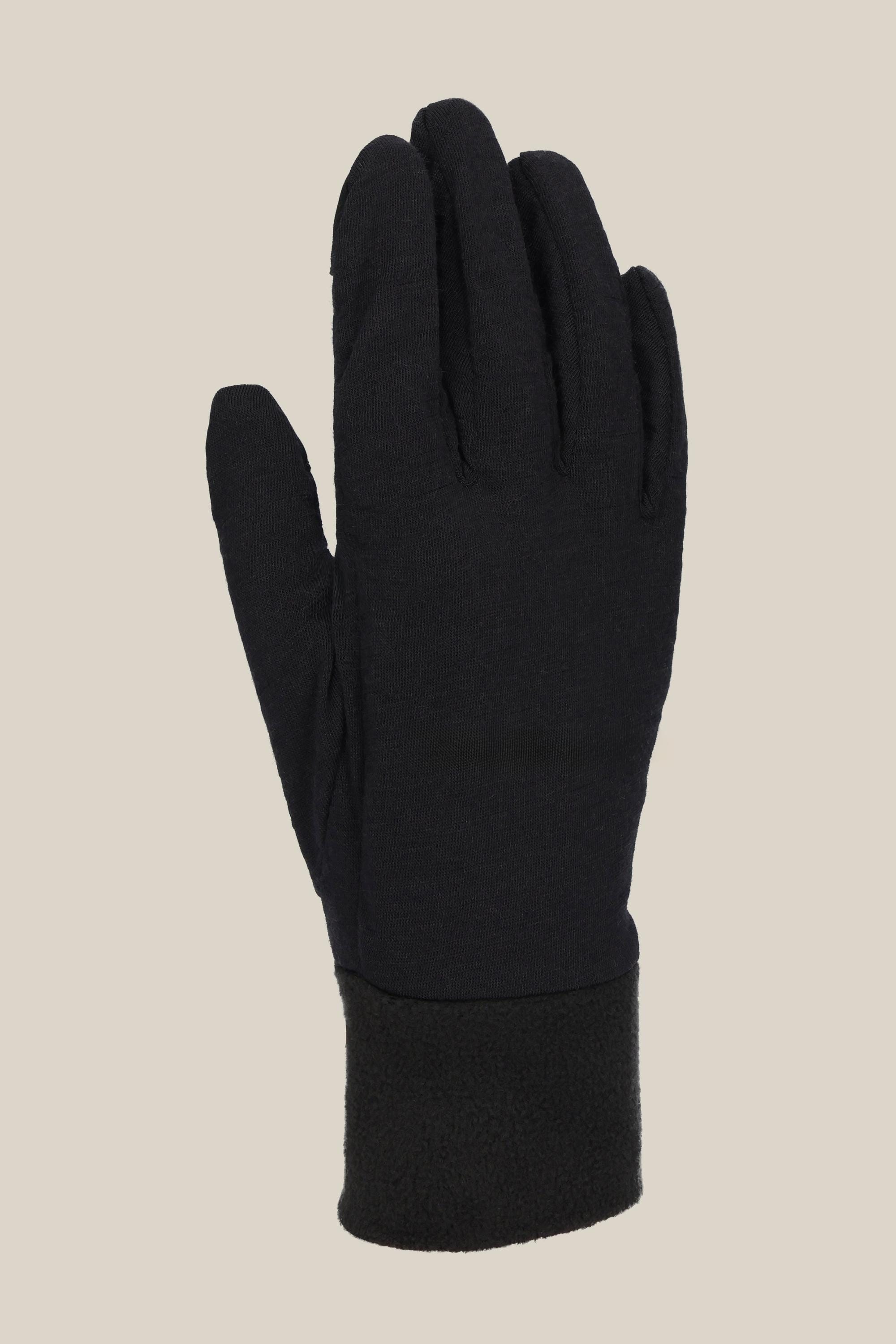 A single 686 Womens Merino Glove Liner in black stands upright against a beige background, showing its soft texture, thick wrist cuff, and cozy polyester-merino blend construction.