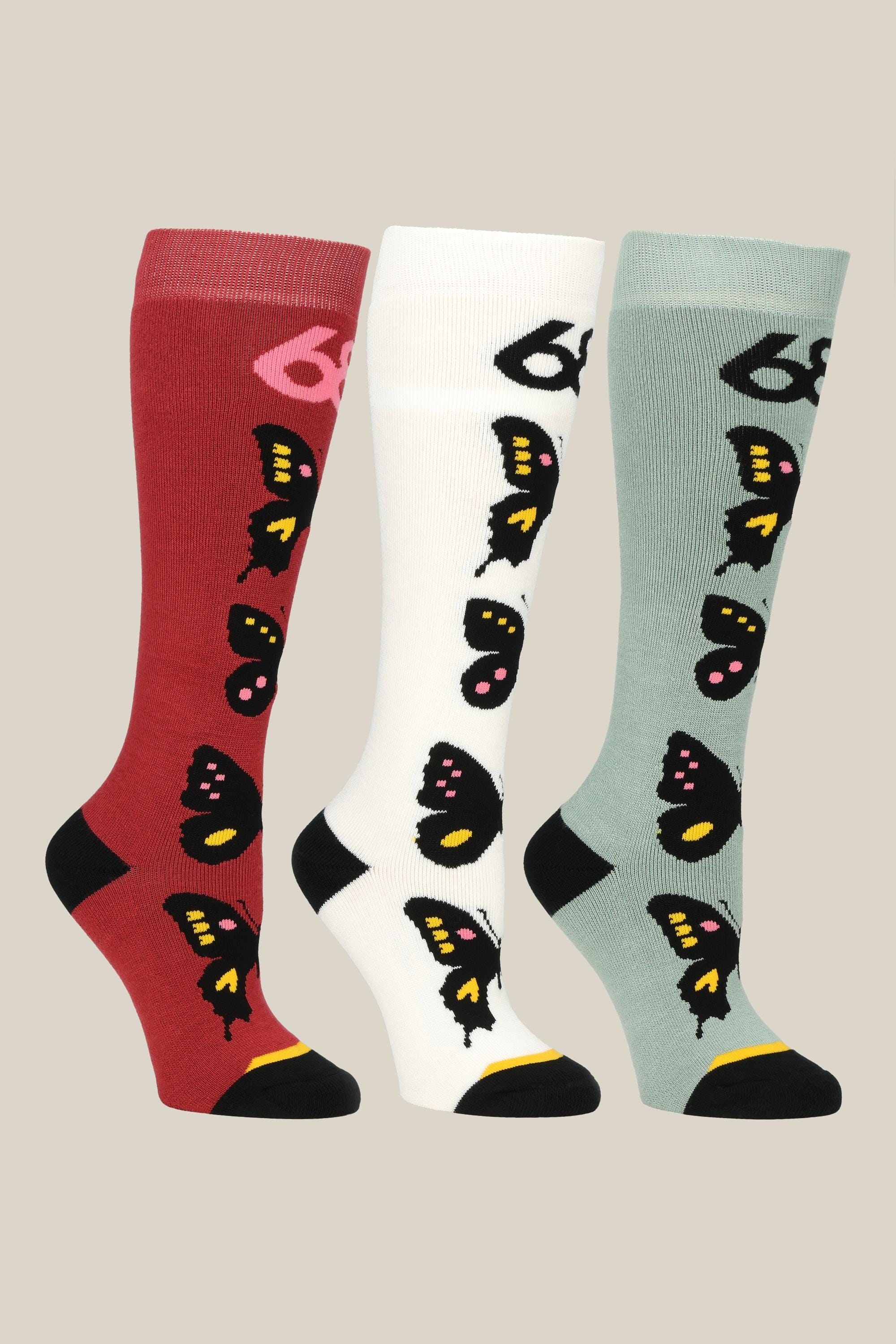 The 686 Womens Butterfly Socks - 3 Pack includes knee-high socks in red, white, and light gray with vibrant butterfly designs and black toes and heels. Stylish and comfortable, these 686 socks are shown upright on a neutral backdrop.