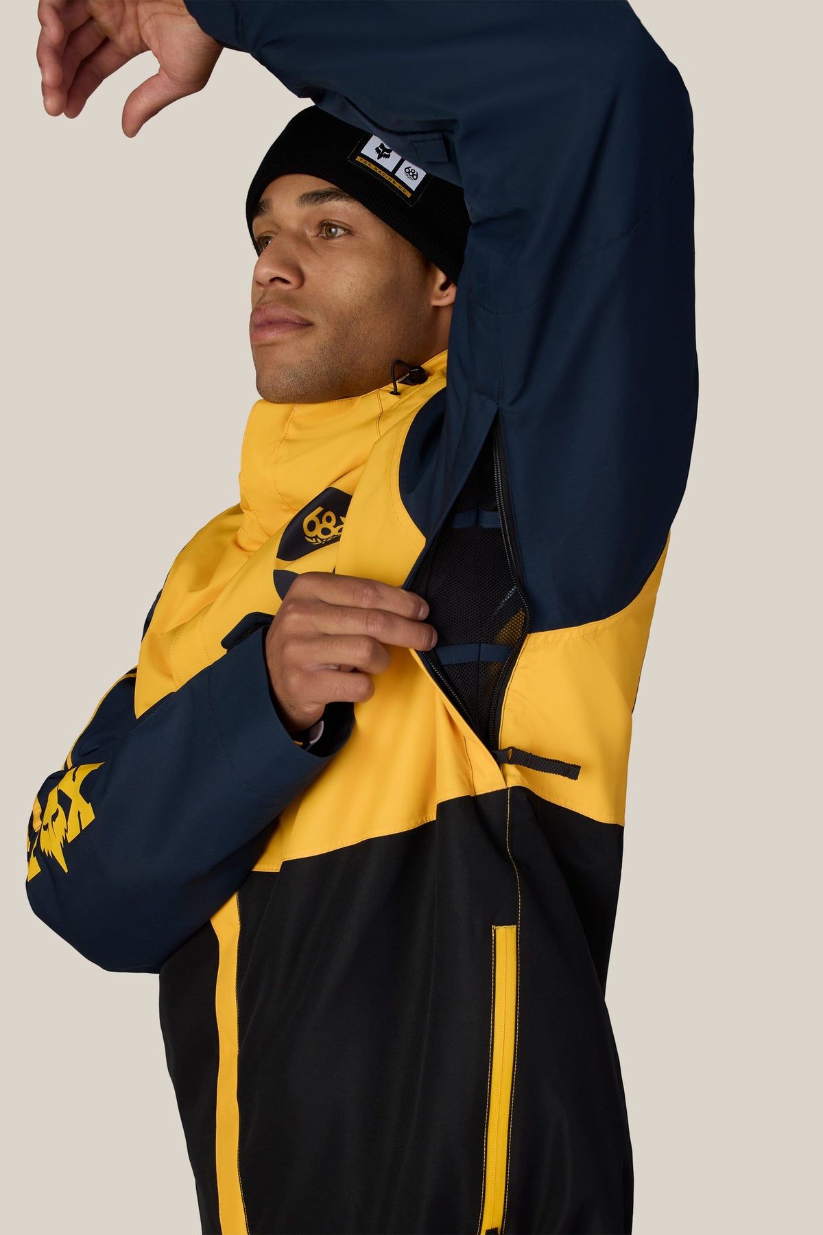 A man wearing a 686 Men’s Fox Racing Spec Insulated Jacket demonstrates the mesh-lined underarm ventilation zipper.