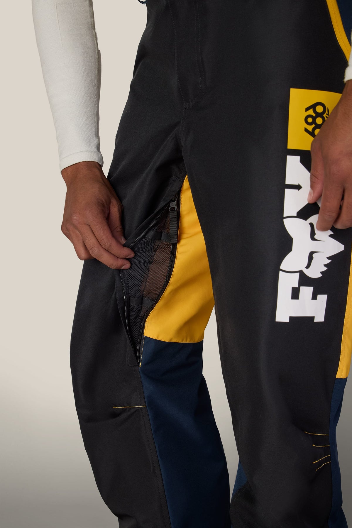 A person opening the mesh-lined thigh vent on a pair of 686 Men’s Fox Racing Spec Shell Pant.