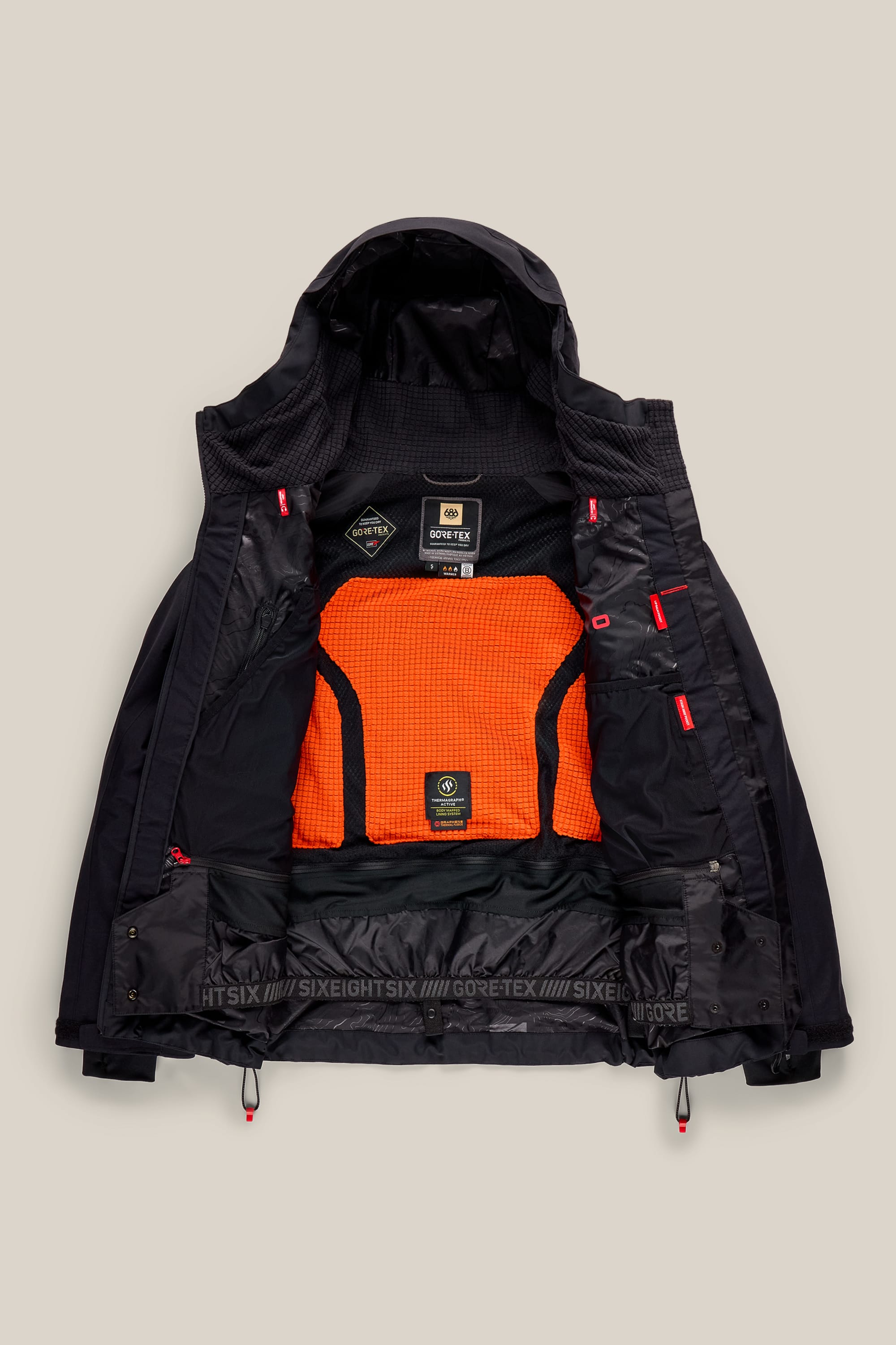 The 686 Women’s GORE-TEX® Scheme Thermagraph® Jacket by 686 is a black, hooded woven jacket featuring an open front that reveals an orange mesh inner lining and multiple black and red interior details—including GORE-TEX and branded labels. Waterproof and stylish, this jacket stands out against a light beige background.